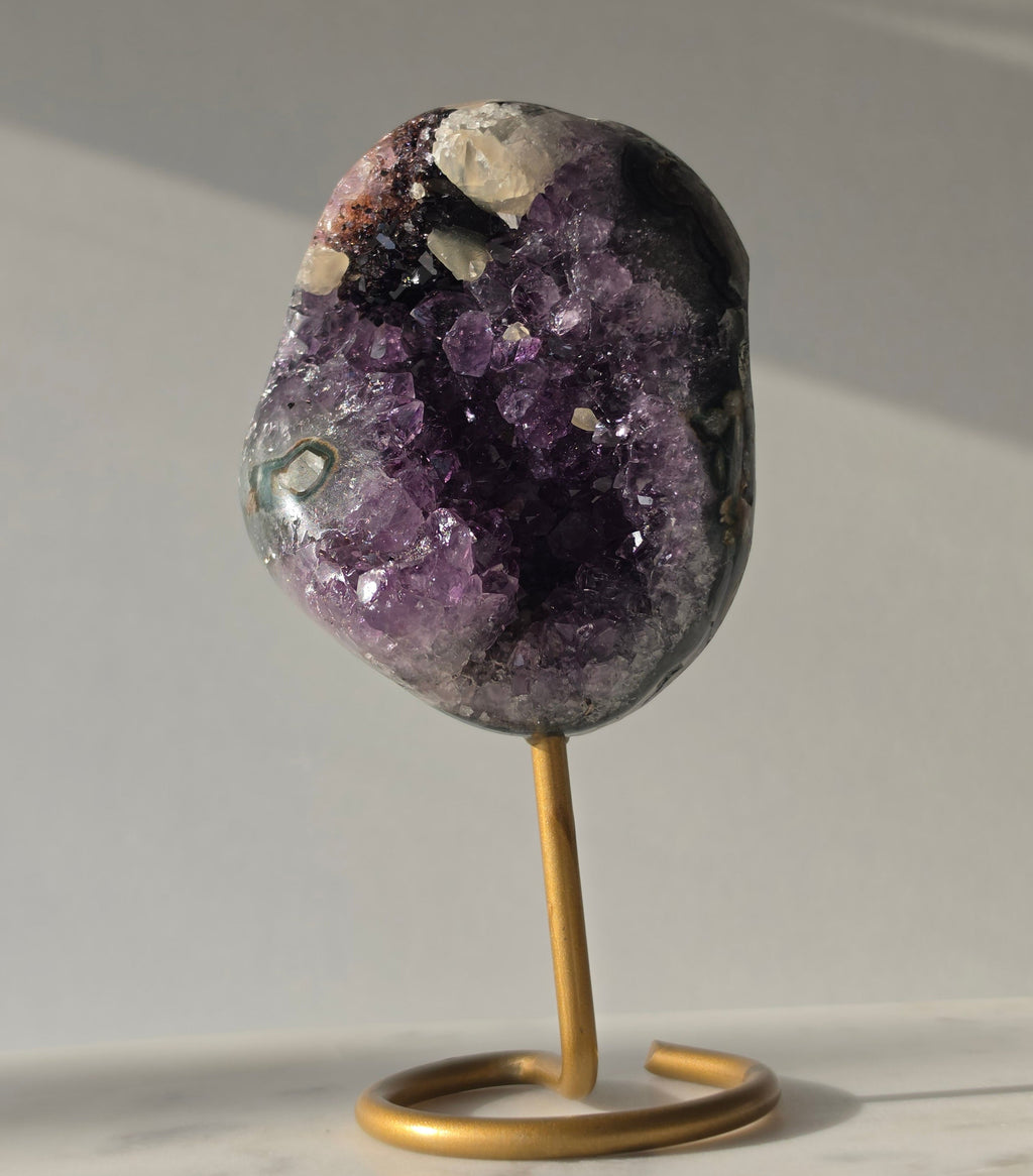 Natural Amethyst Stalactite with Calcite inclusions and blush red tones on a luxury gold display stand