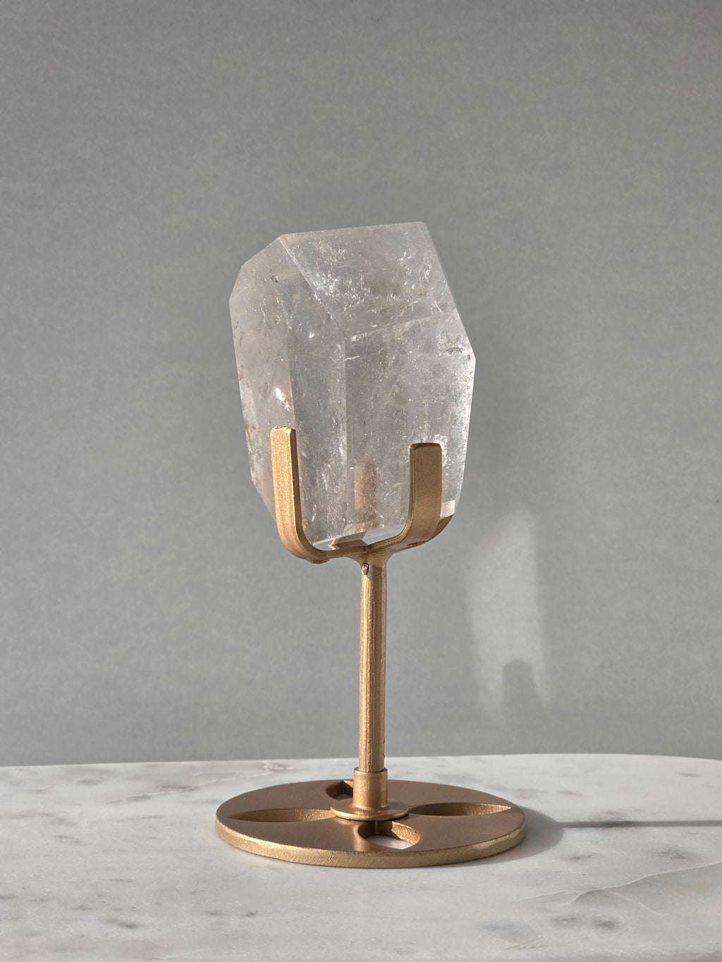 Clear Quartz freeform crystal with subtle smoky-grey translucence, natural internal inclusions and luminous clarity, displayed on an elegant gold-finished stand.