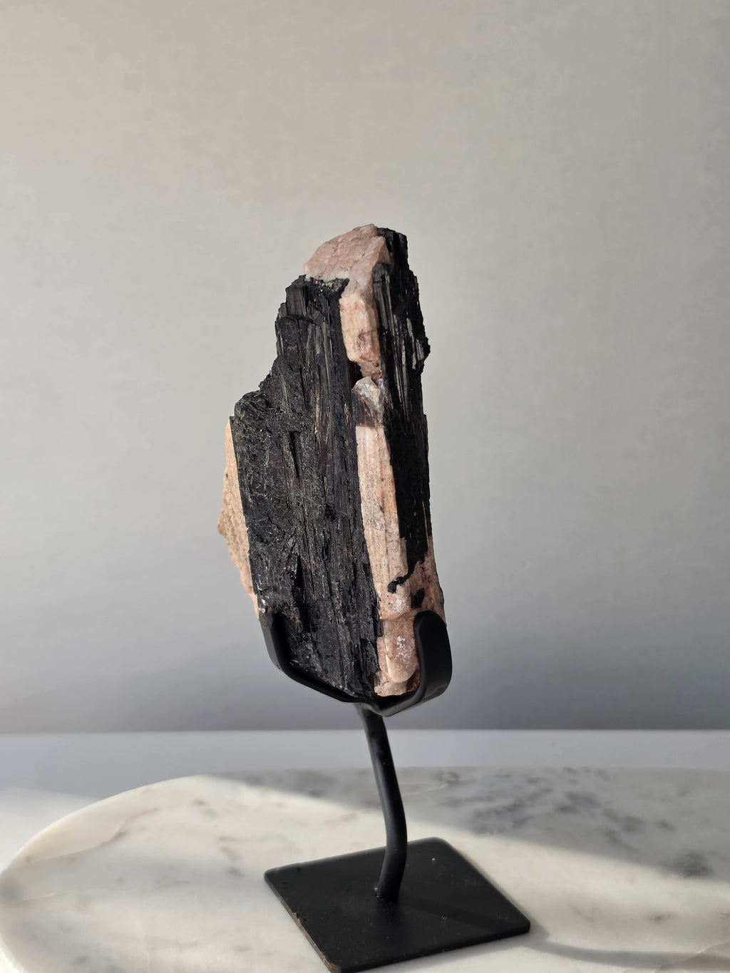 Black Tourmaline on Feldspar matrix from Brazil featuring naturally formed black crystals, contrasting pale matrix, black display stand, 910g, 19.5 × 6.5cm.
