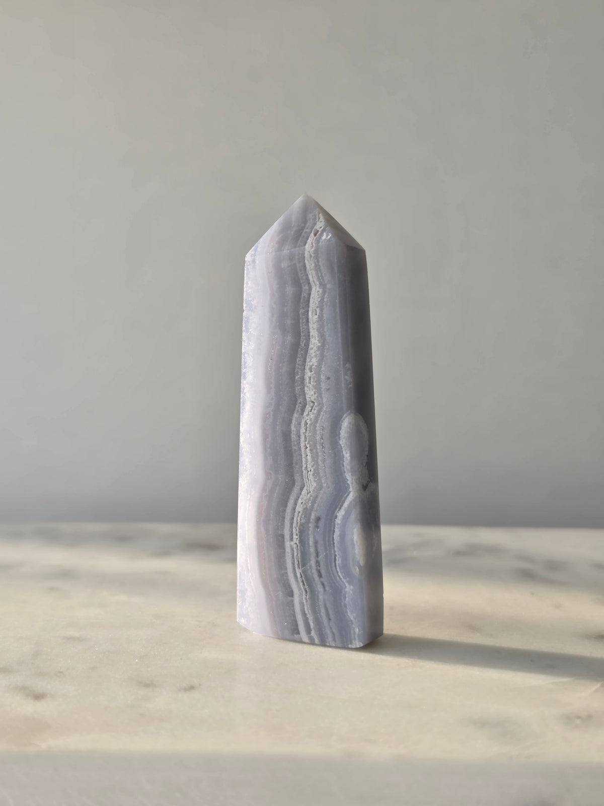 Natural Blue Lace Agate crystal point with soft blue and white banding, polished finish and unique natural formations