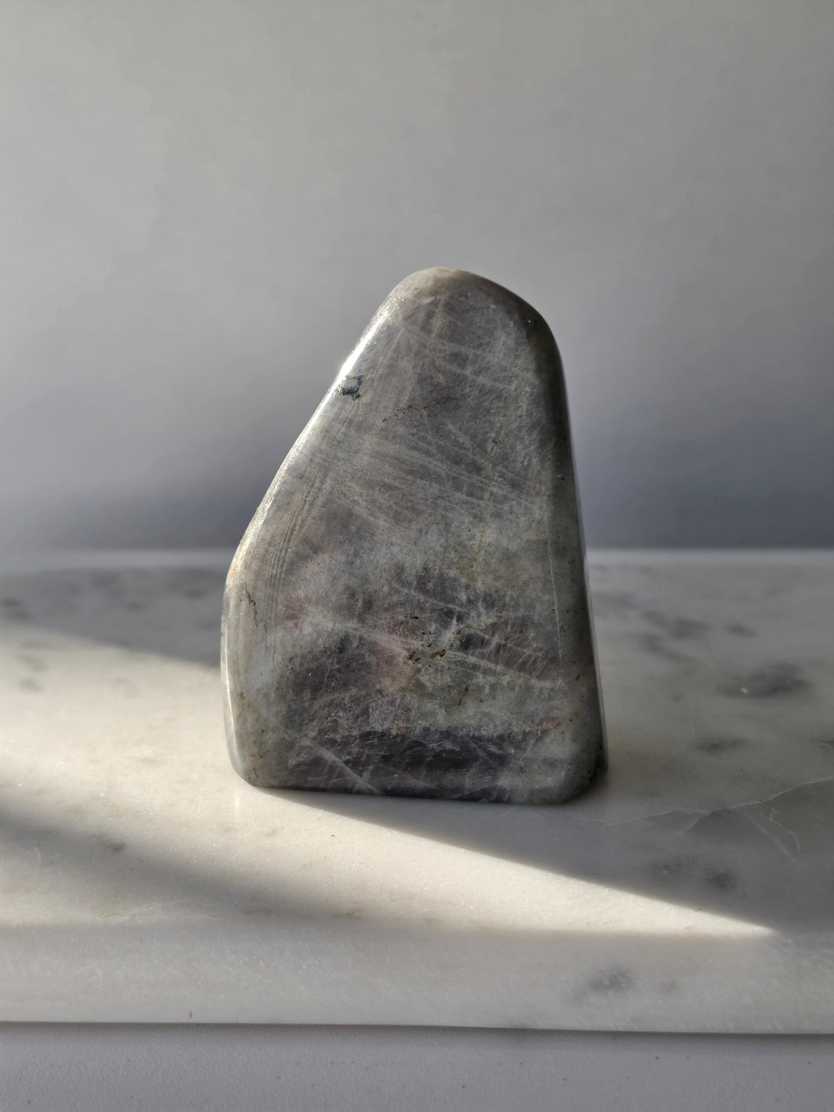 259g polished Labradorite cut base with smoky grey and charcoal colouring, natural silvery patterns and blue turquoise iridescence on the front.