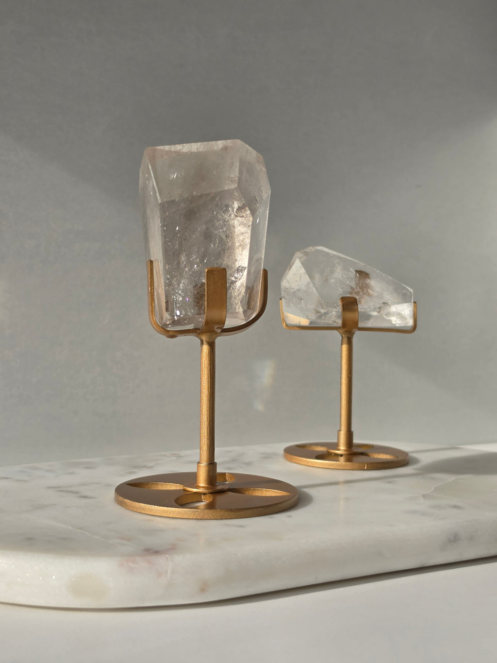 Clear Quartz freeform crystal with natural internal inclusions and luminous clarity, displayed on an elegant gold-finished stand.