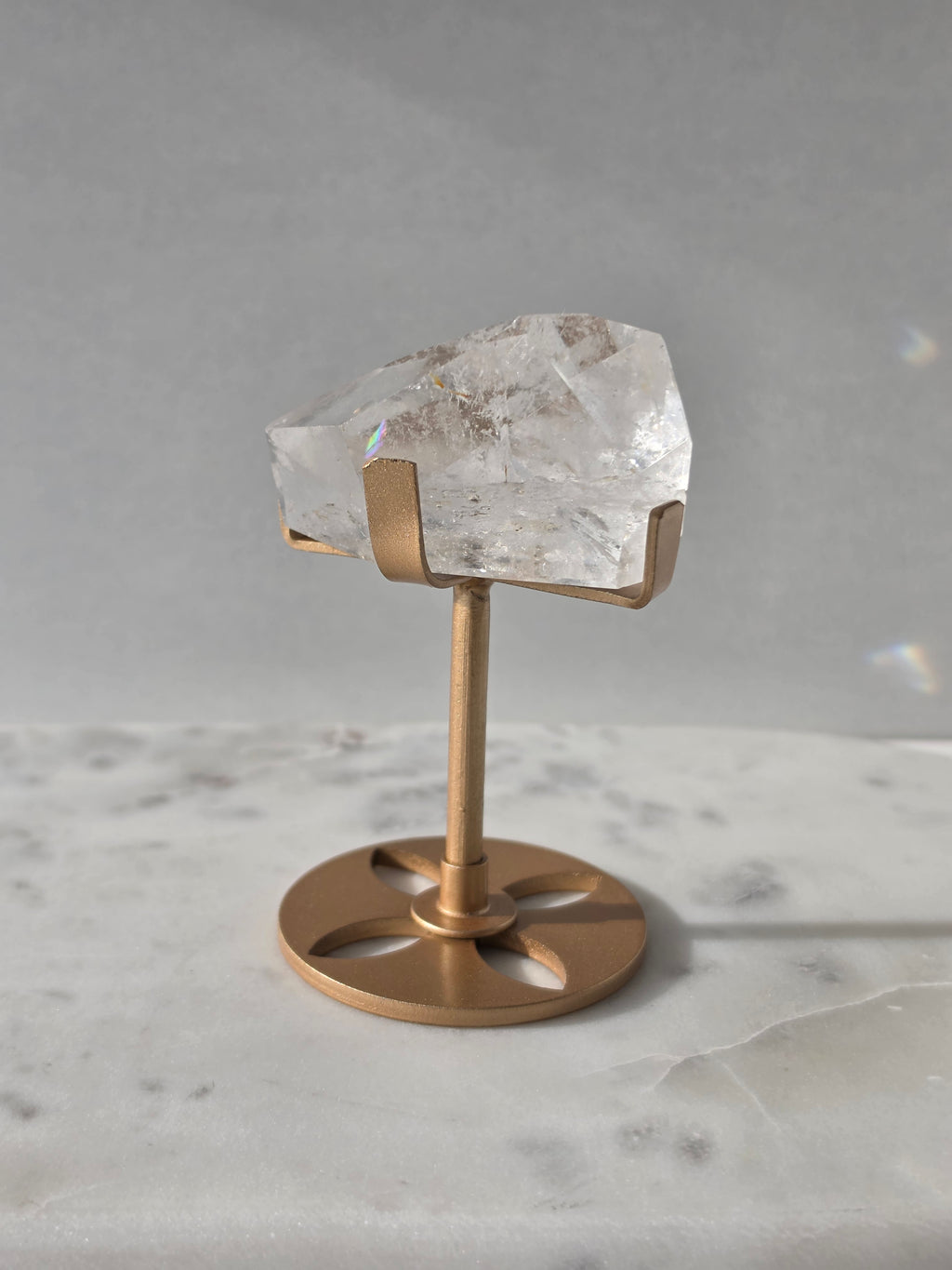 Clear Quartz freeform crystal with natural internal inclusions and luminous clarity, displayed on an elegant gold-finished stand.