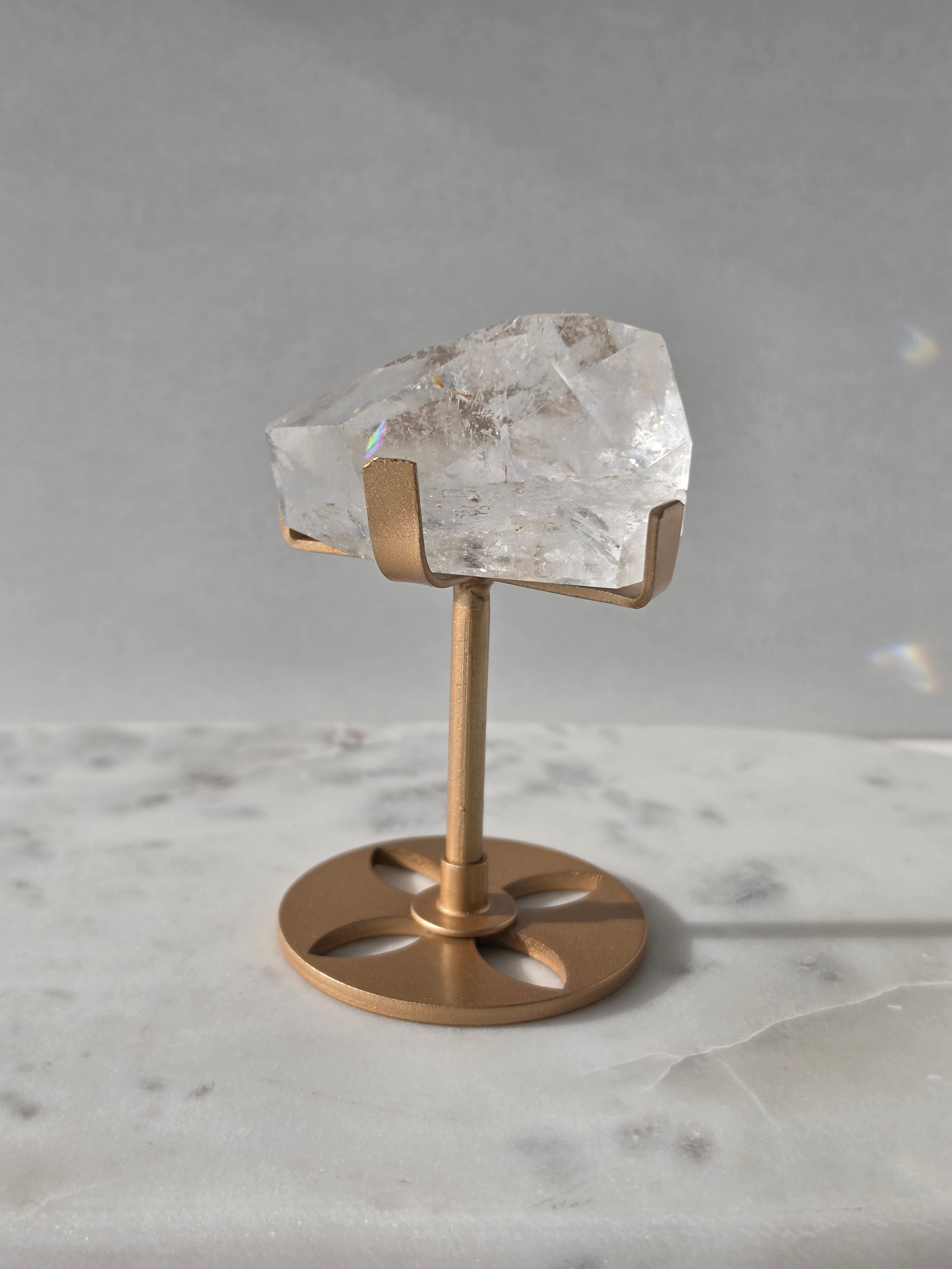Clear Quartz freeform crystal with natural internal inclusions and luminous clarity, displayed on an elegant gold-finished stand.