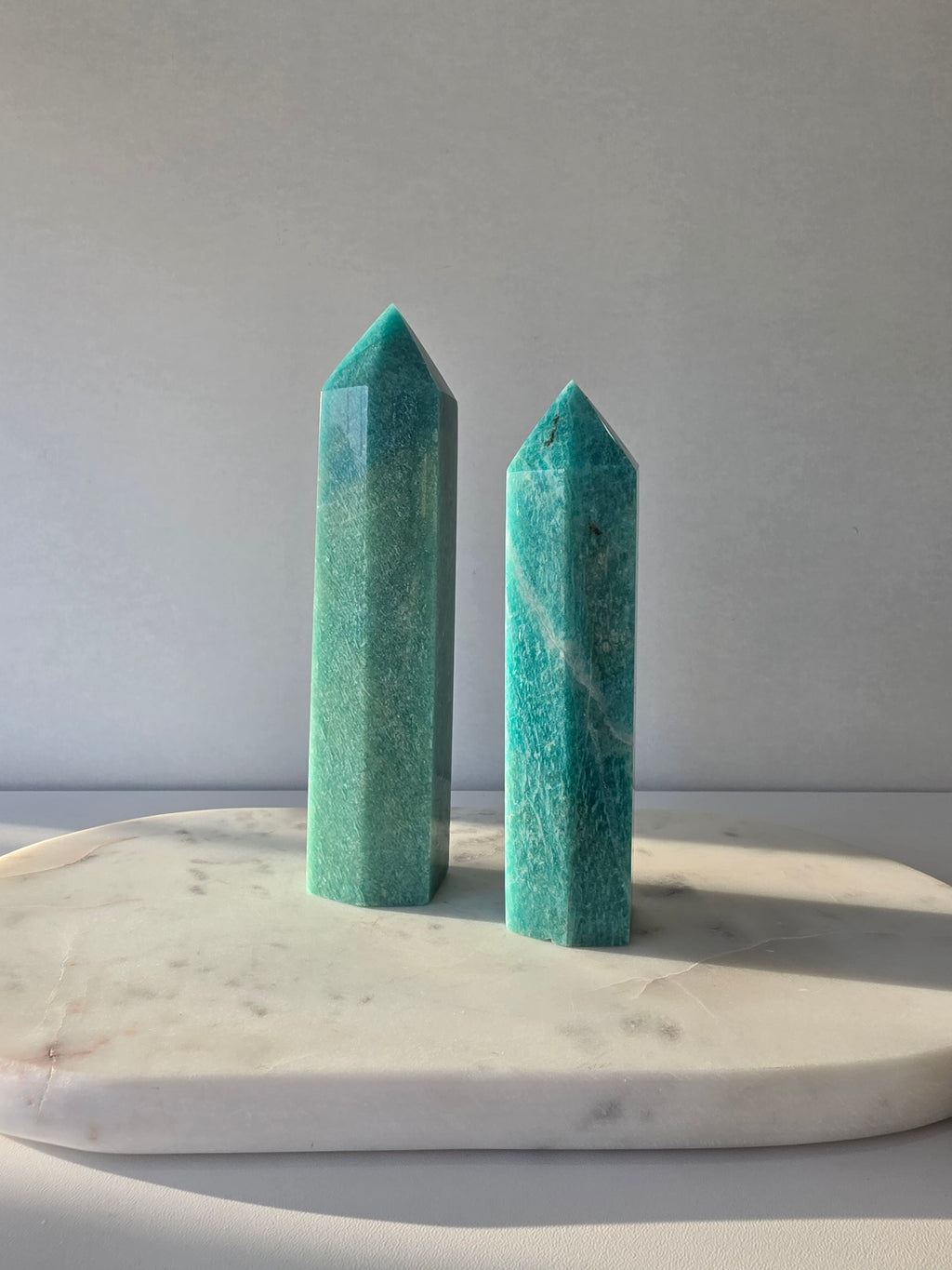 Natural Amazonite tower in soft mint and sea-green tones with subtle blue-green variations, polished geometric point and delicate natural inclusions, displayed as a luxury crystal statement piece.