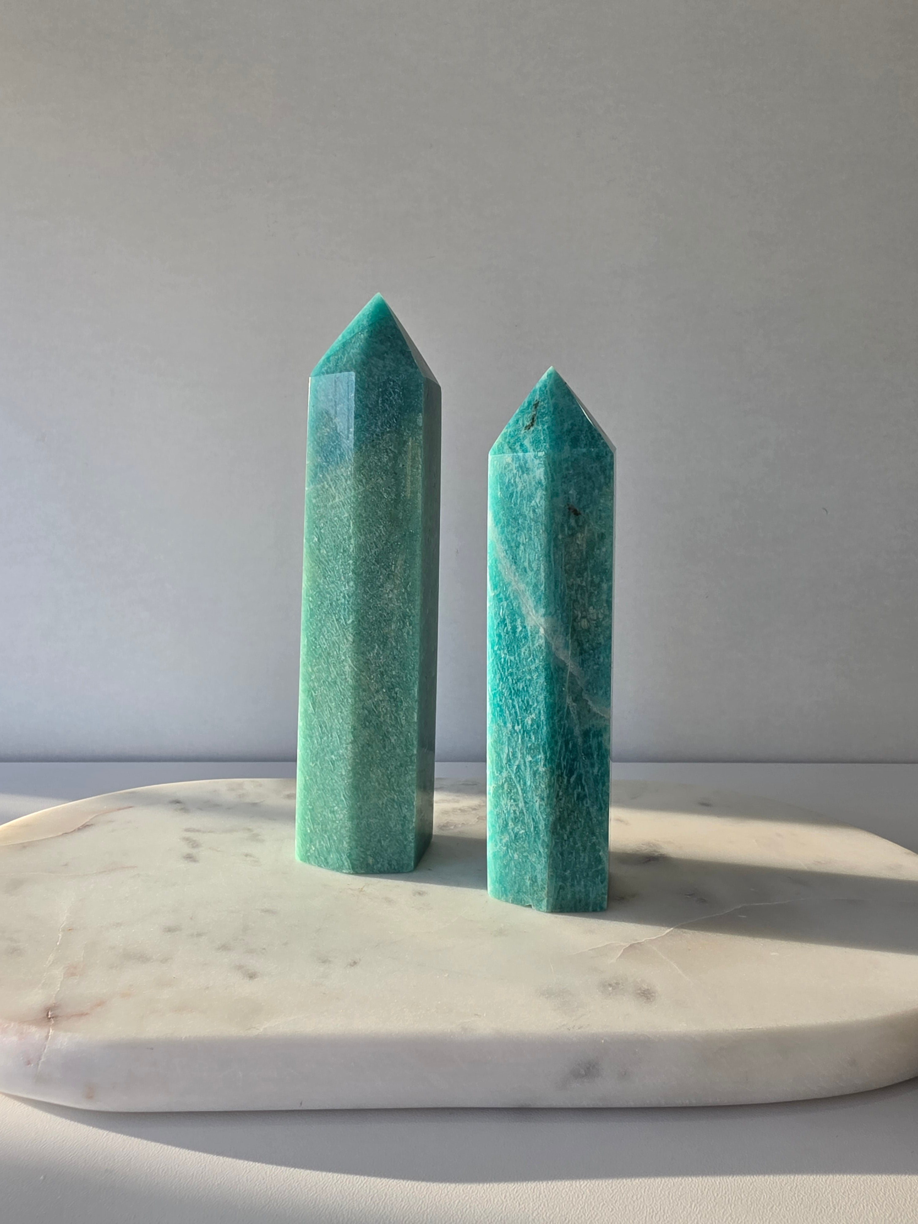 Natural Amazonite tower in soft mint and sea-green tones with subtle blue-green variations, polished geometric point and delicate natural inclusions, displayed as a luxury crystal statement piece.