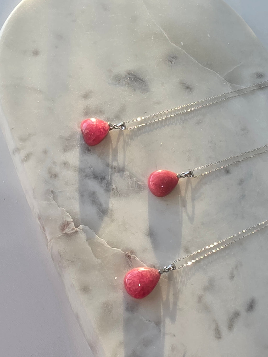 Natural Rhodochrosite teardrop pendant in 925 sterling silver with matching silver chain, featuring vibrant pink tones and unique natural patterns