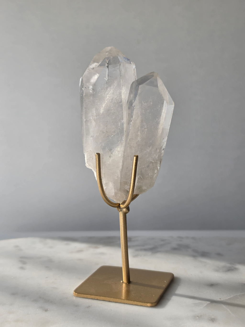 Clear Quartz Lemurian crystal on gold stand featuring exceptional clarity, natural rainbow inclusions, internal formations and striking crystal points