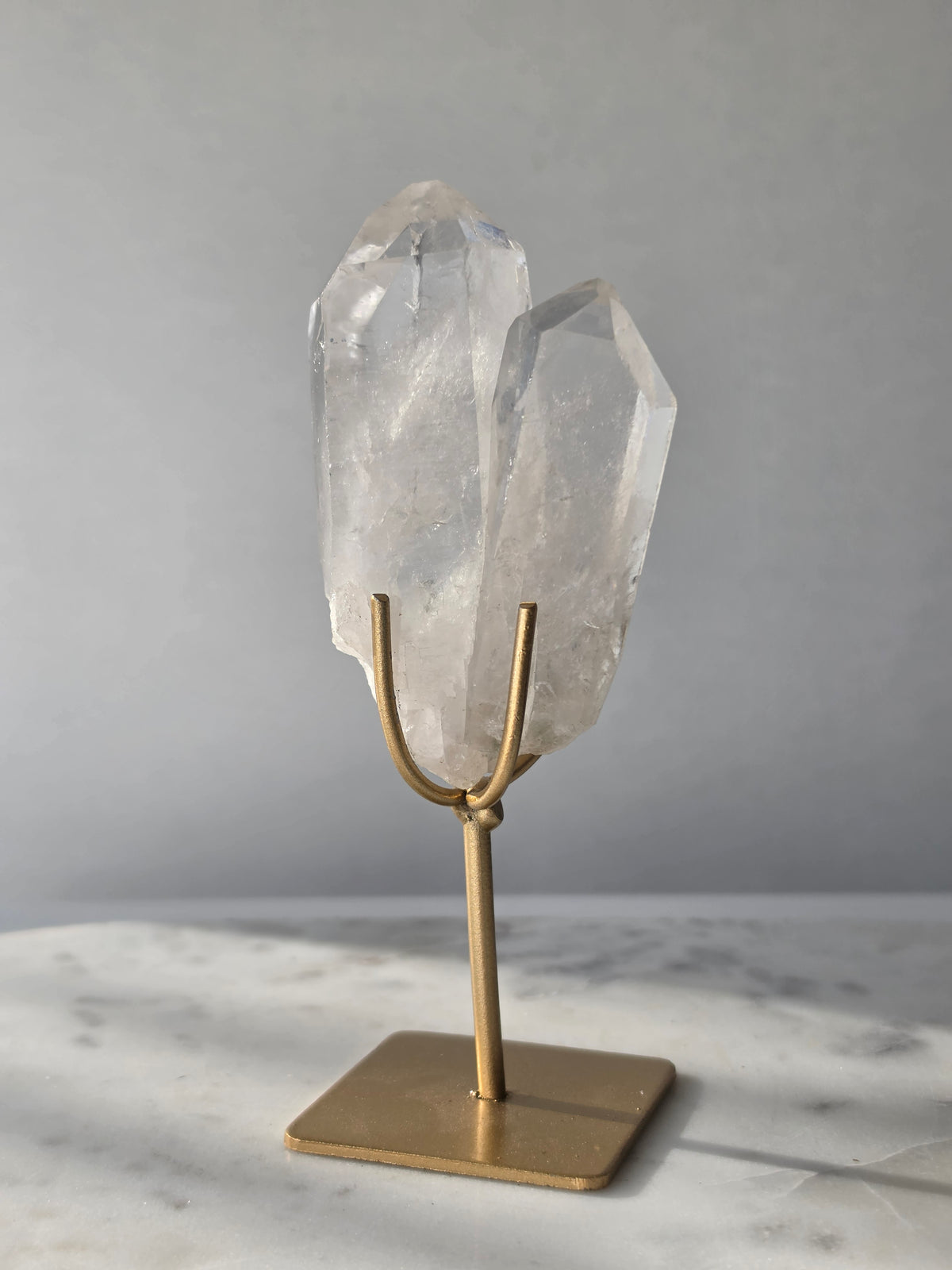 Clear Quartz Lemurian crystal on gold stand featuring exceptional clarity, natural rainbow inclusions, internal formations and striking crystal points