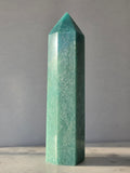 Natural Amazonite tower in soft mint and sea-green tones with subtle blue-green variations, polished geometric point and delicate natural inclusions, displayed as a luxury crystal statement piece.