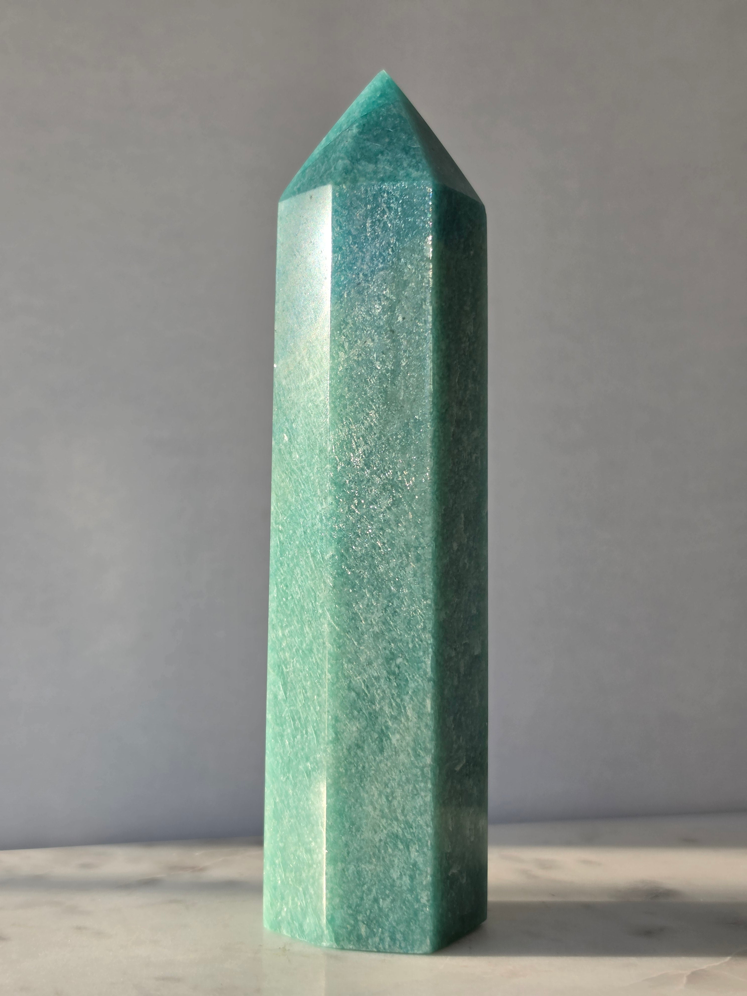 Natural Amazonite tower in soft mint and sea-green tones with subtle blue-green variations, polished geometric point and delicate natural inclusions, displayed as a luxury crystal statement piece.