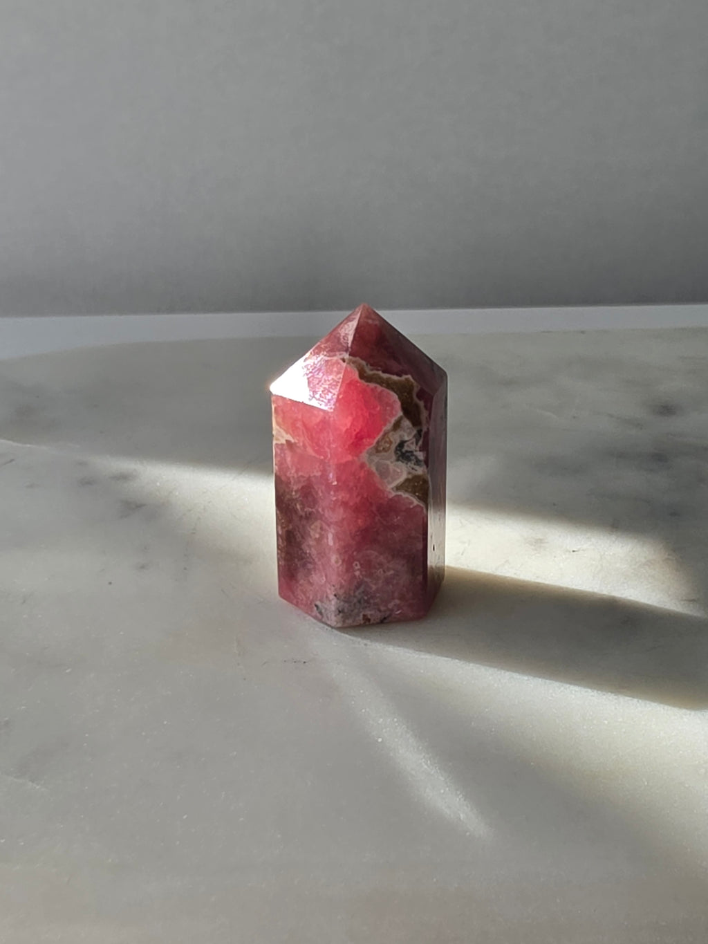 Polished Argentine Rhodochrosite crystal point with deep raspberry pink colour and intricate cream, blush and dark mineral banding, 37g, 4cm.