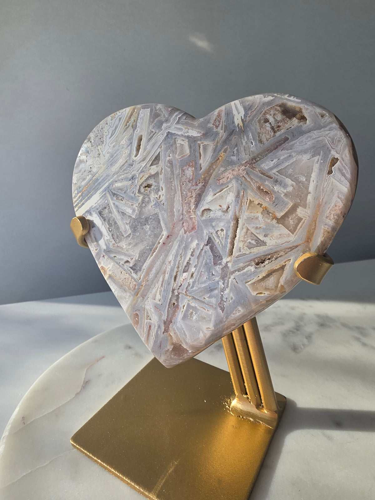 Brazilian Pink Amethyst heart on gold stand featuring intricate white palhetados splinter-like formations, soft blush pink colouring and natural mineral inclusions