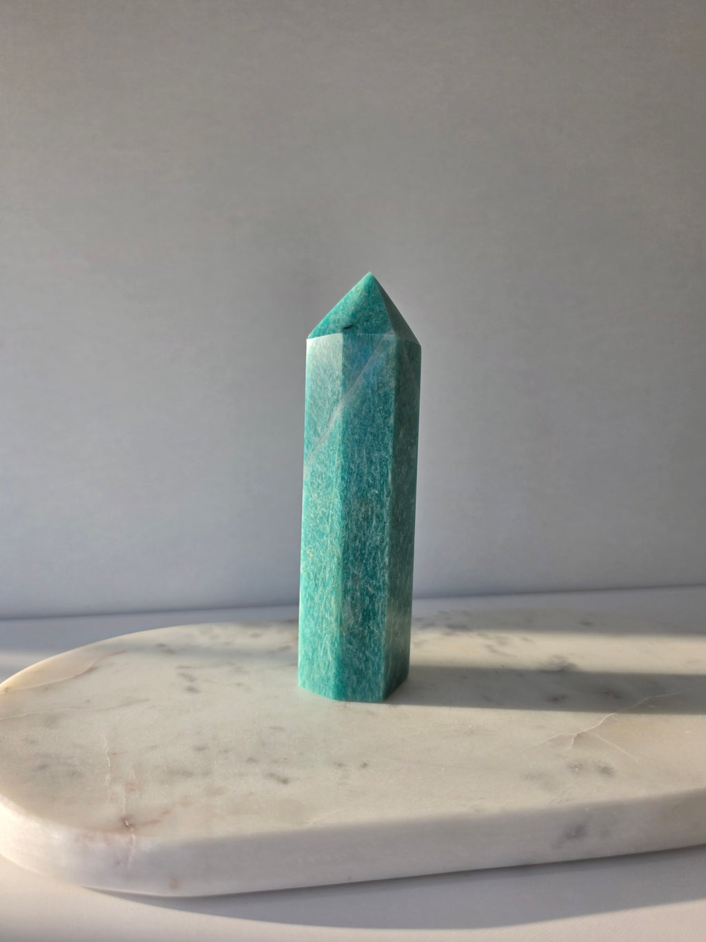 Natural Amazonite tower in soft mint and sea-green tones with subtle blue-green variations, polished geometric point and delicate natural inclusions, displayed as a luxury crystal statement piece.