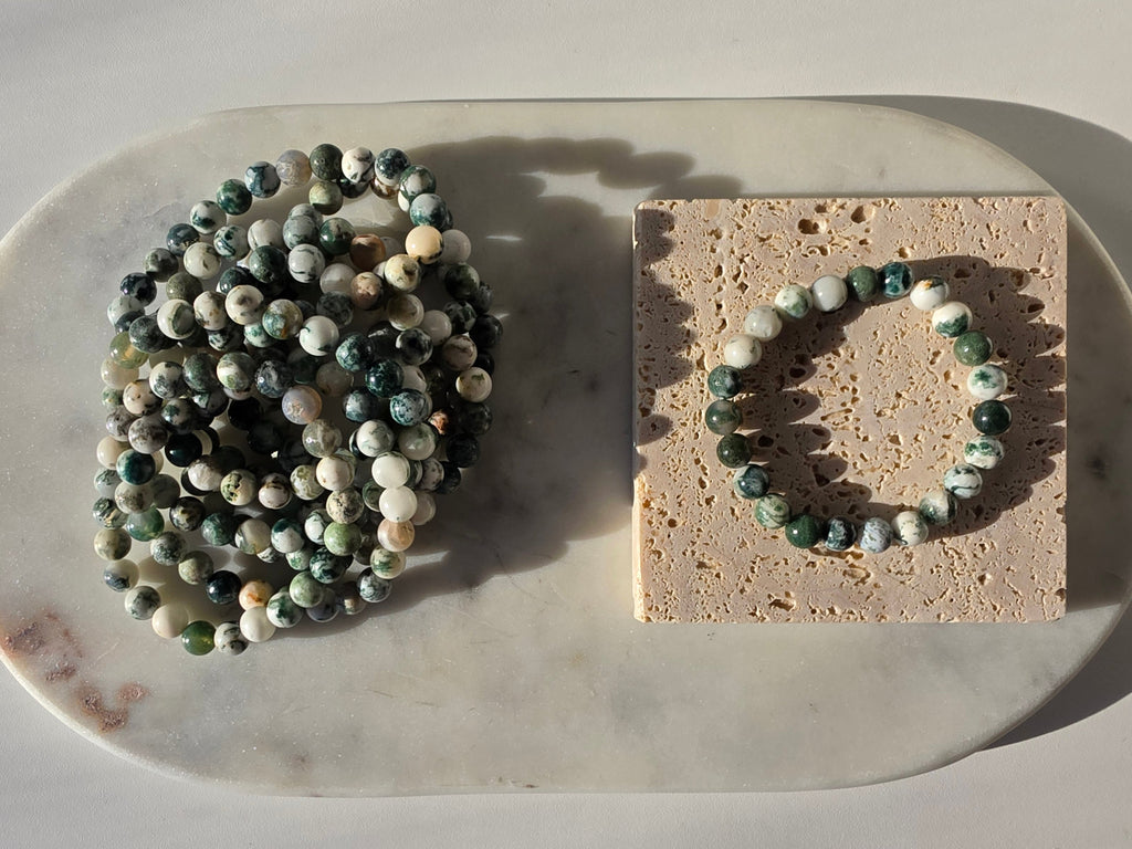 High-grade Moss Agate beaded bracelets featuring polished natural gemstones with rich forest green, soft ivory, and intricate moss-like inclusions, handcrafted with premium quality stones and photographed in natural light.
