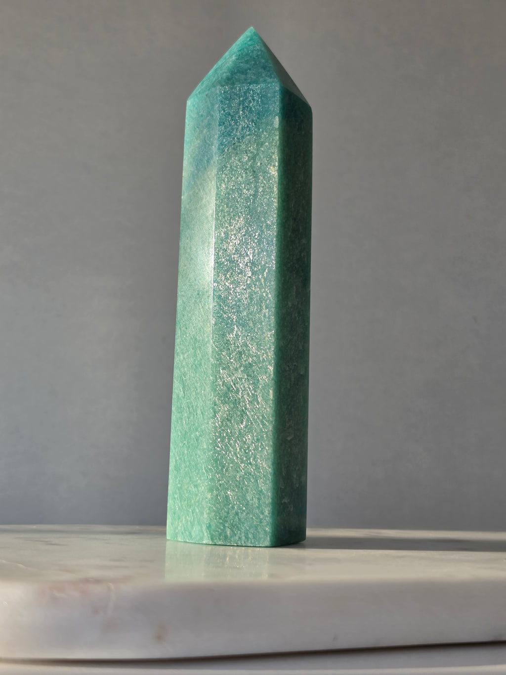 Natural Amazonite tower in soft mint and sea-green tones with subtle blue-green variations, polished geometric point and delicate natural inclusions, displayed as a luxury crystal statement piece.