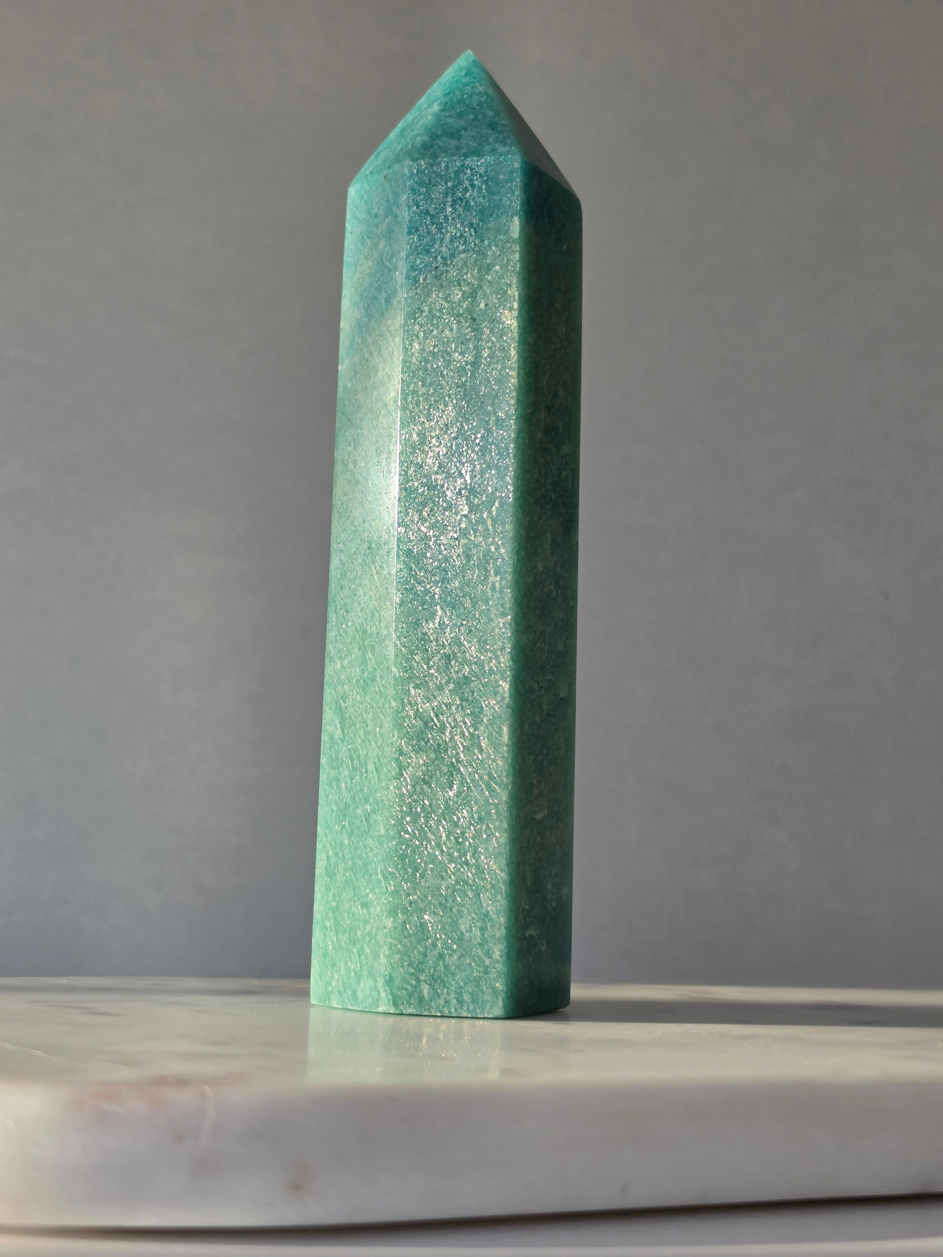 Natural Amazonite tower in soft mint and sea-green tones with subtle blue-green variations, polished geometric point and delicate natural inclusions, displayed as a luxury crystal statement piece.