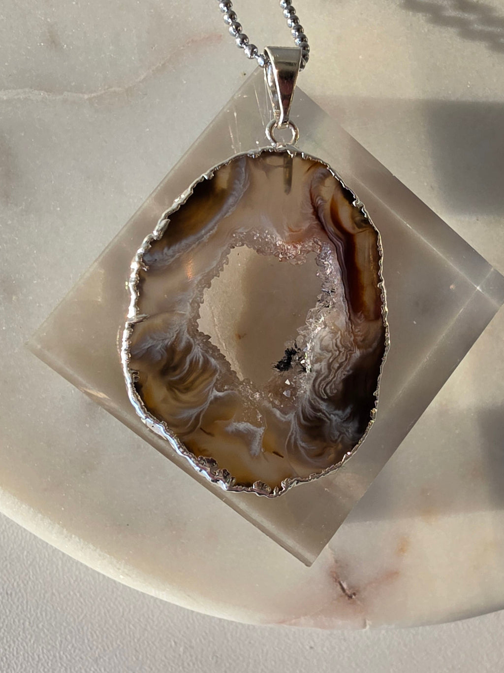 "Brazilian Agate Geode Slice Pendant in natural [brown/black/grey] tones on a silver plated chain with sparkling druzy crystal formations"