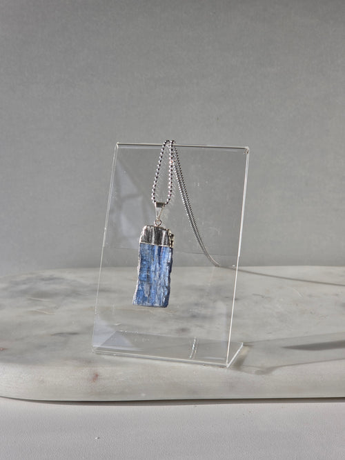 Natural Blue Kyanite raw crystal pendant with silver-plated cap from the Stone & Bloom Raw Luxe Collection, featuring deep blue tones and natural crystal texture.