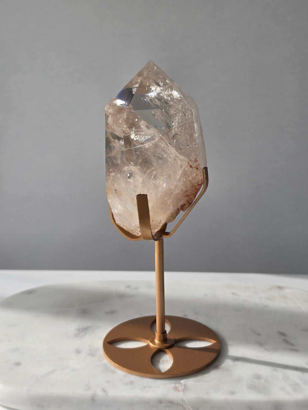 High-grade Nepalese Pink Himalayan Quartz statement piece, 606g and 19cm tall, featuring delicate pink tones, translucent crystal formations and natural inclusions, displayed on a gold stand.