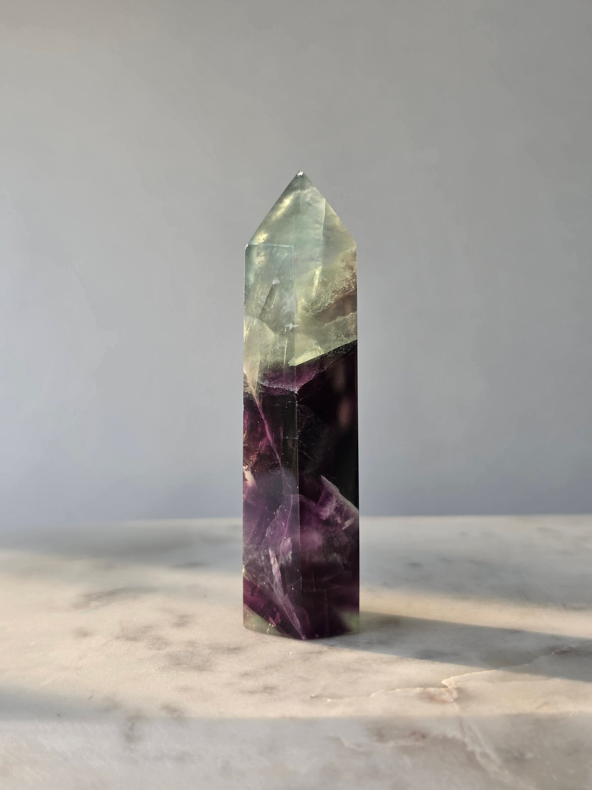 Natural Fluorite crystal point with deep purple and light green colour zoning, transparent polished finish and unique internal formations