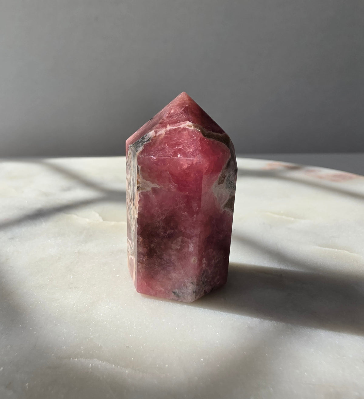 Polished Argentine Rhodochrosite crystal point with deep raspberry pink colour and intricate cream, blush and dark mineral banding, 37g, 4cm.