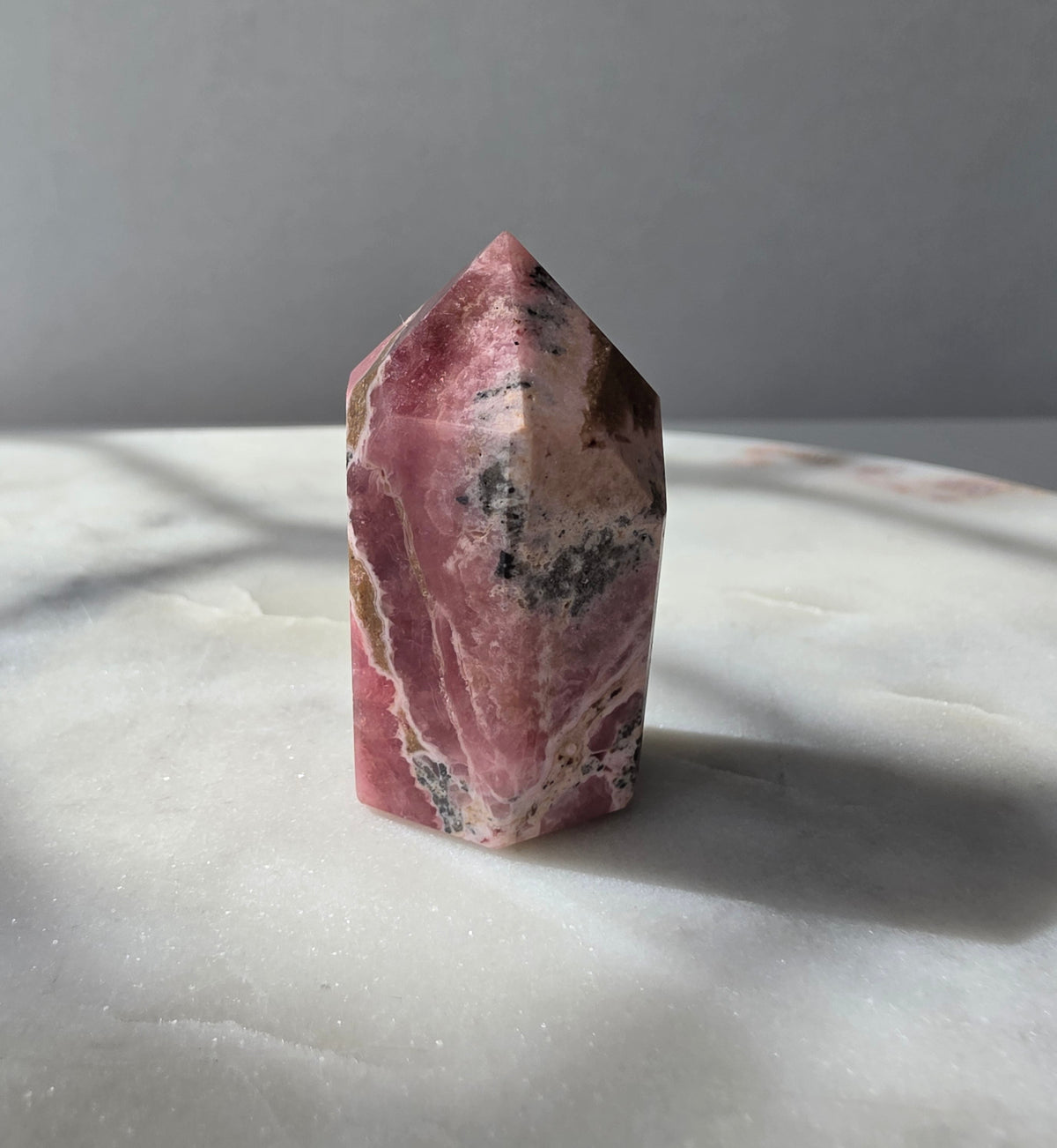 Polished Argentine Rhodochrosite crystal point with deep raspberry pink colour and intricate cream, blush and dark mineral banding, 37g, 4cm.