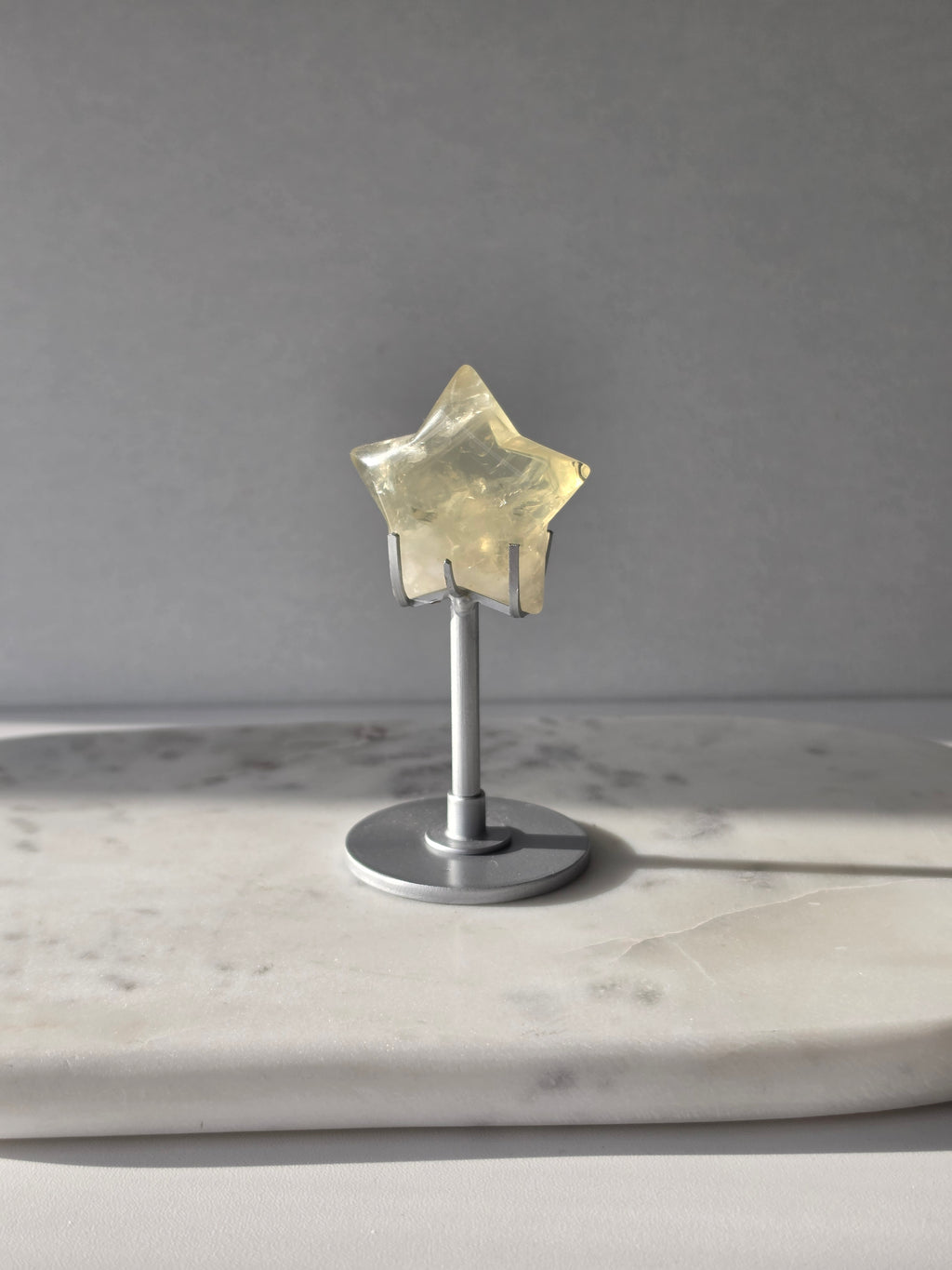 Natural citrine crystal star on a silver stand, featuring translucent golden tones and unique crystal formations, Stone & Bloom statement decor