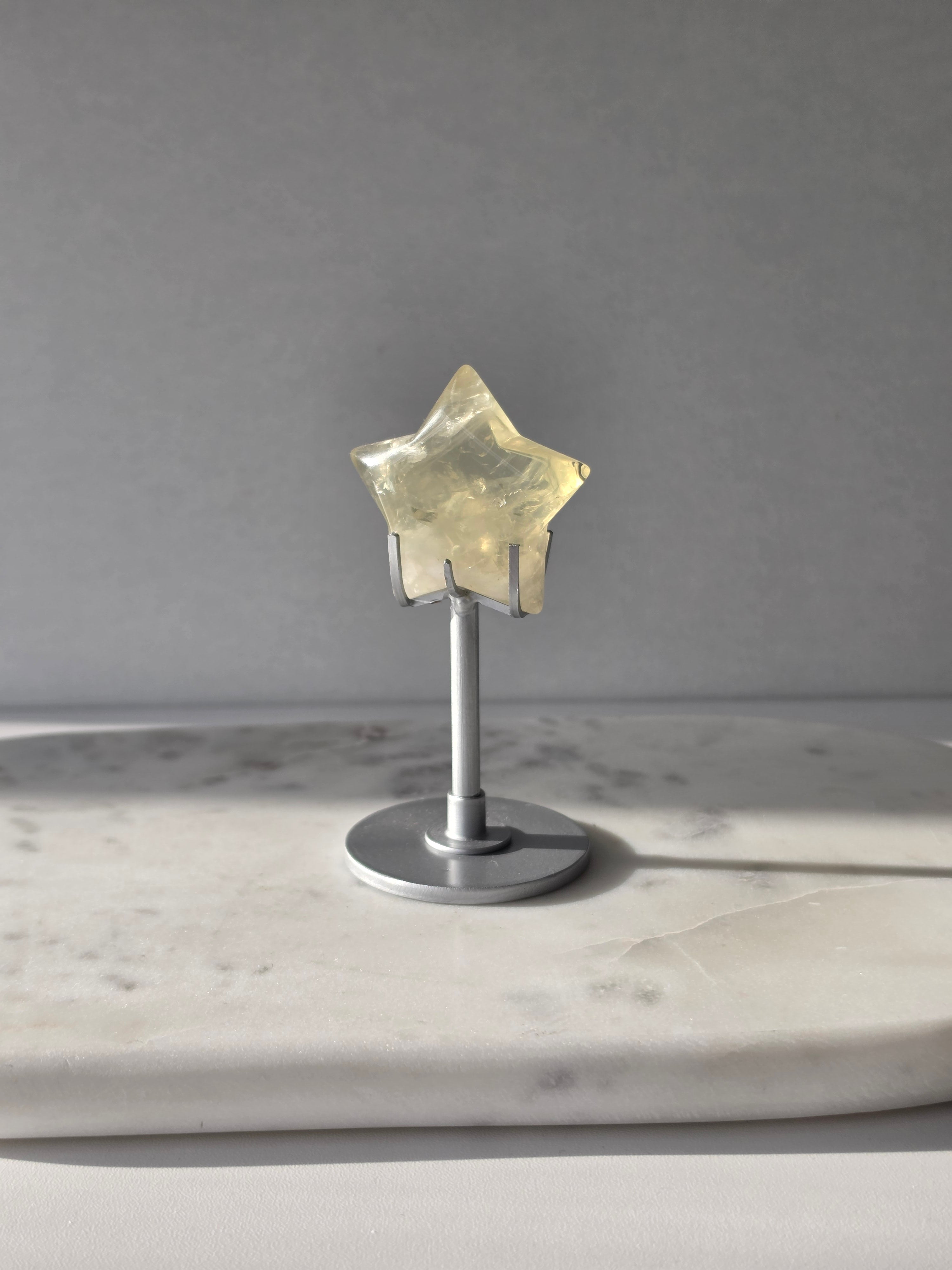 Natural citrine crystal star on a silver stand, featuring translucent golden tones and unique crystal formations, Stone & Bloom statement decor