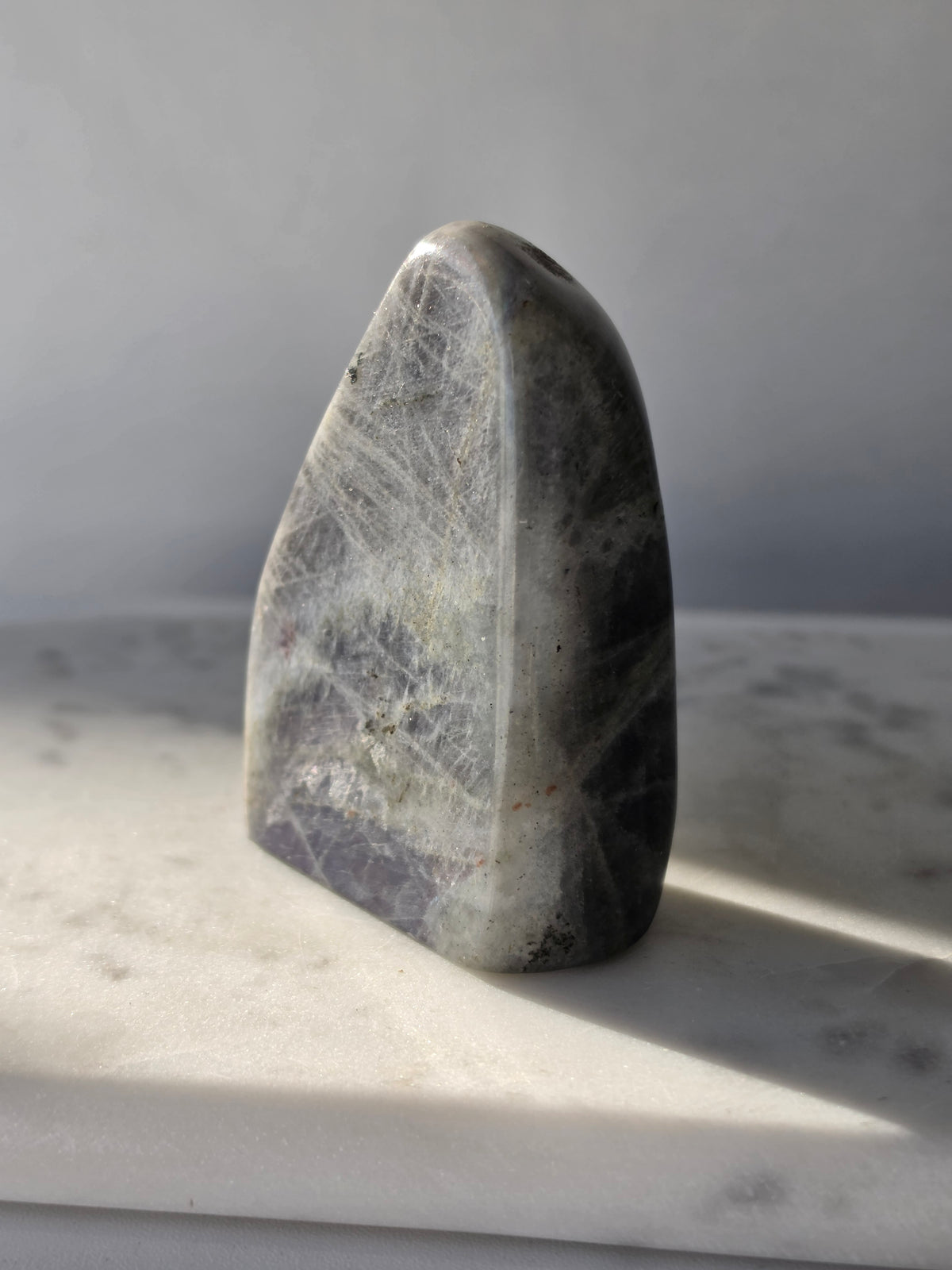 259g polished Labradorite cut base with smoky grey and charcoal colouring, natural silvery patterns and blue turquoise iridescence on the front.
