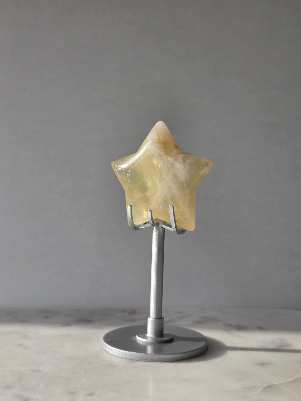 Natural citrine crystal star on a silver stand, featuring translucent golden tones and unique crystal formations, Stone & Bloom statement decor