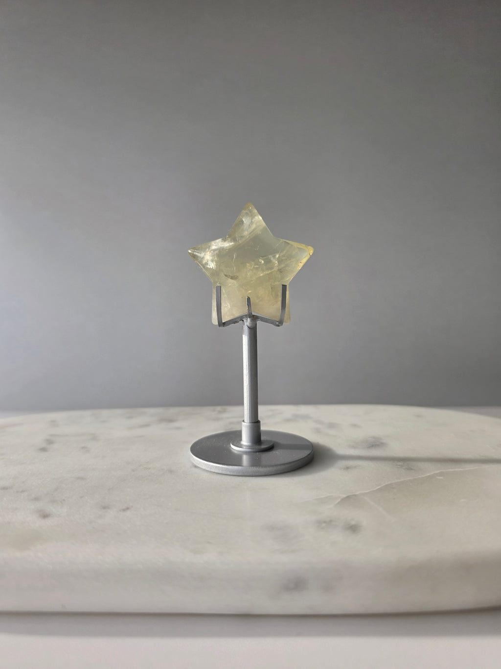 Natural citrine crystal star on a silver stand, featuring translucent golden tones and unique crystal formations, Stone & Bloom statement decor