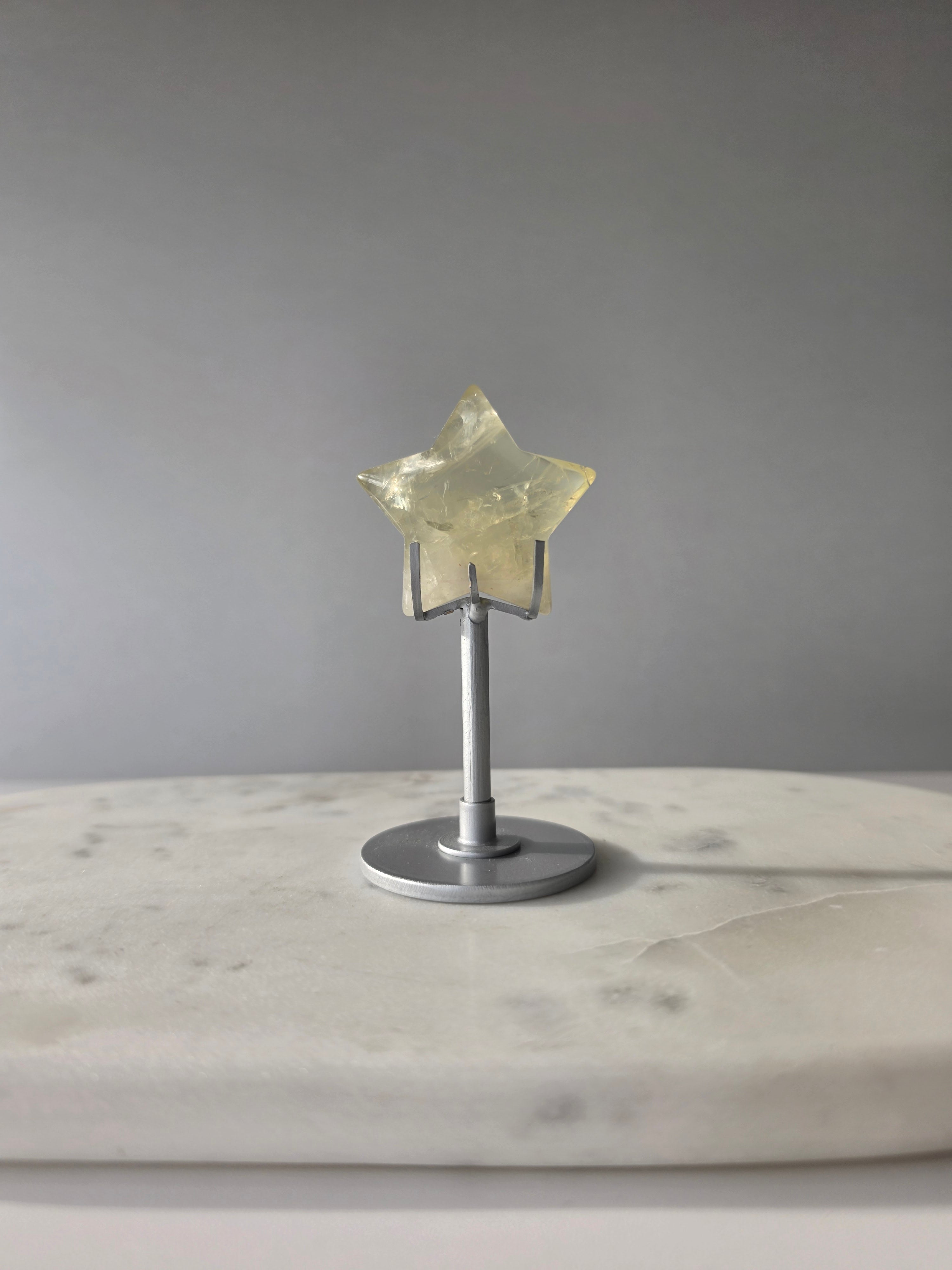 Natural citrine crystal star on a silver stand, featuring translucent golden tones and unique crystal formations, Stone & Bloom statement decor