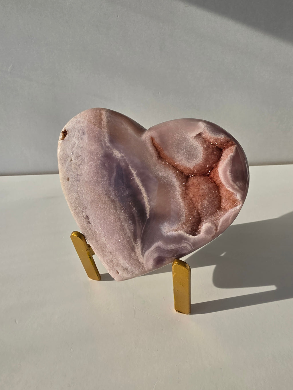 Natural Brazilian Pink Amethyst heart crystal on gold metal stand featuring blush pink banding and sparkling druzy quartz, luxury crystal home décor by Stone & Bloom.