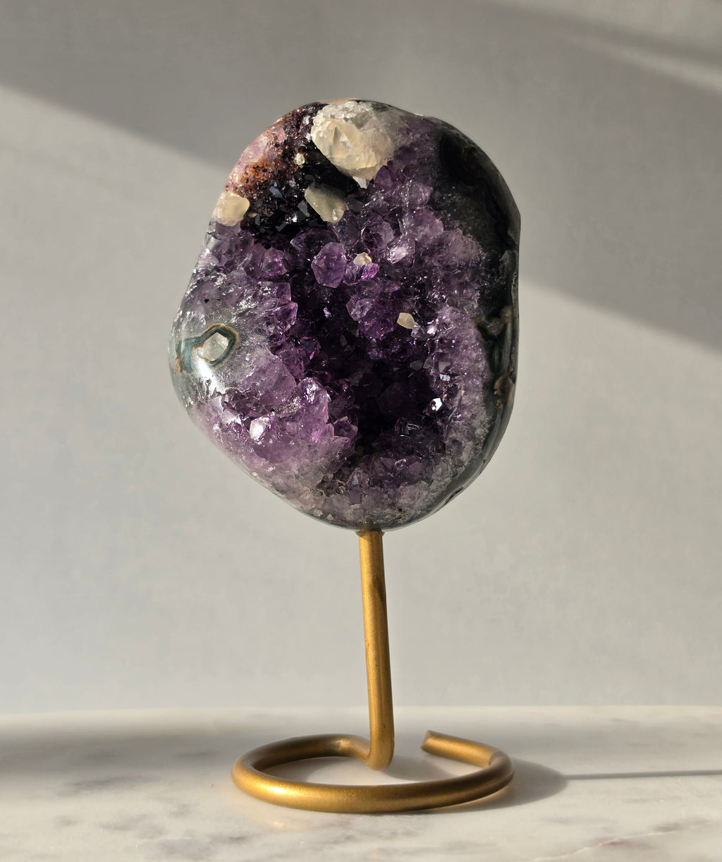 Natural Amethyst Stalactite with Calcite inclusions and blush red tones on a luxury gold display stand