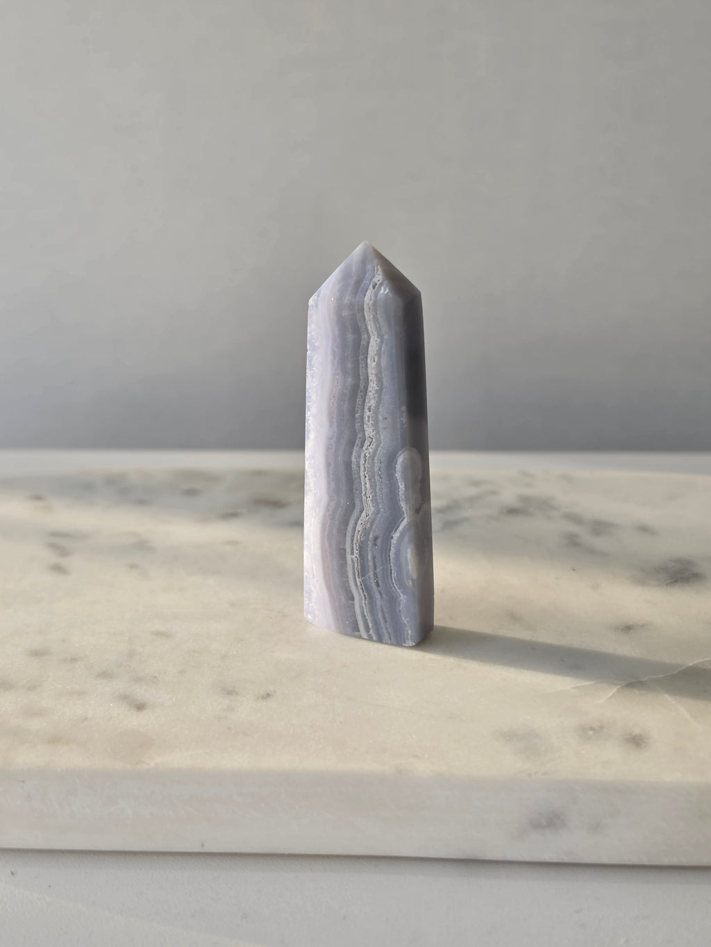Natural Blue Lace Agate crystal point with soft blue and white banding, polished finish and unique natural formations
