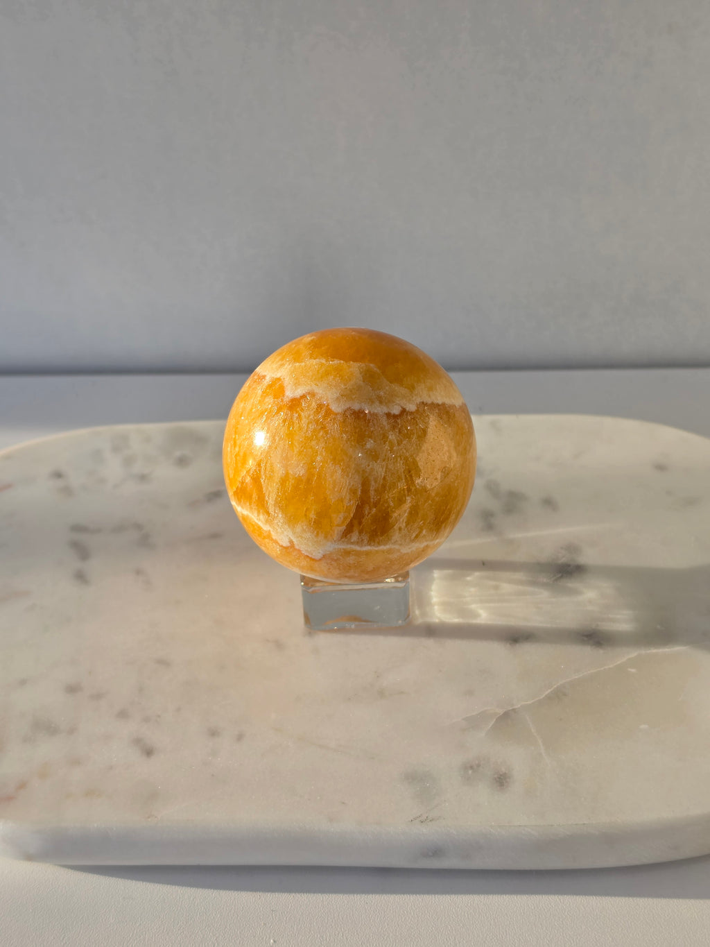 Natural Orange Calcite Sphere with warm golden-orange banding, polished to a high shine and hand-selected by Stone & Bloom.