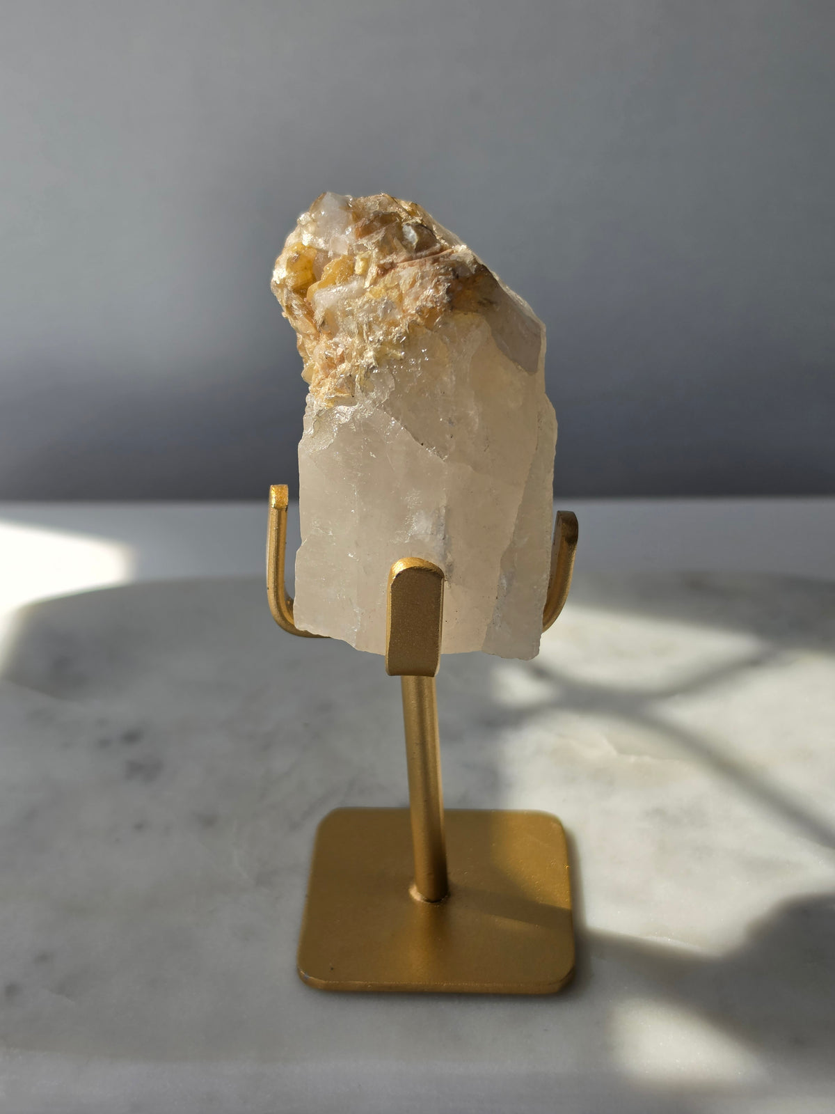 Brazilian Golden Mica on Matrix mineral specimen featuring shimmering golden mica crystals within a pale translucent matrix, displayed on a gold-toned stand.