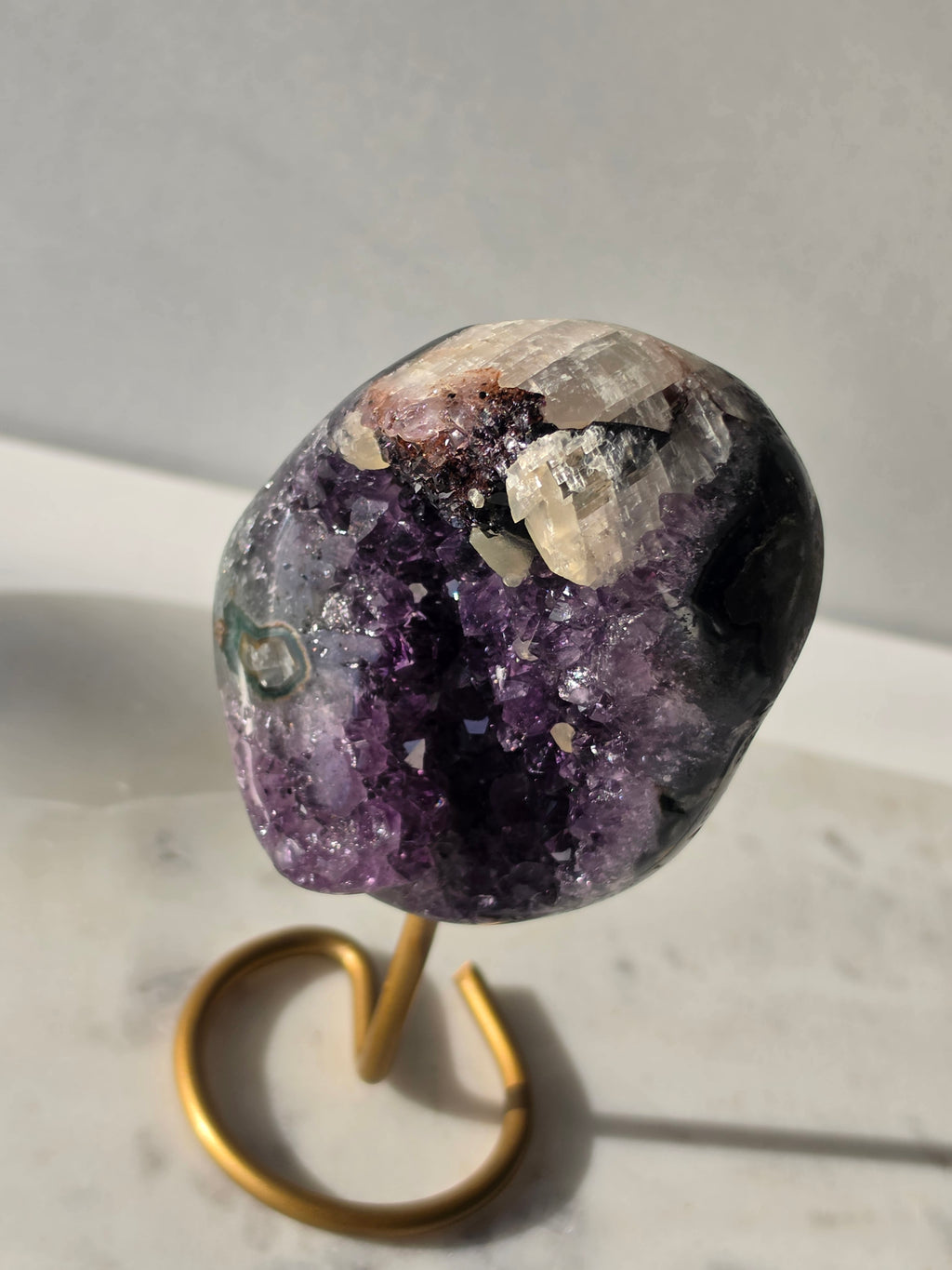 Natural Amethyst Stalactite with Calcite inclusions and blush red tones on a luxury gold display stand