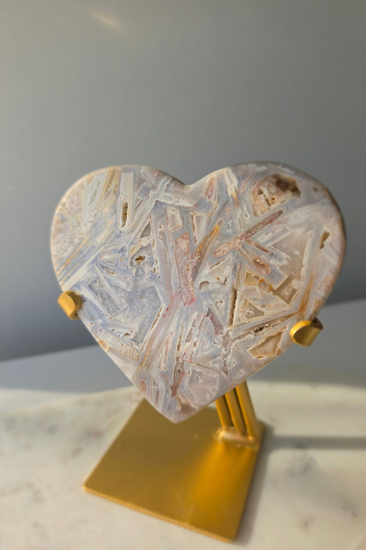 Brazilian Pink Amethyst heart on gold stand featuring intricate white palhetados splinter-like formations, soft blush pink colouring and natural mineral inclusions