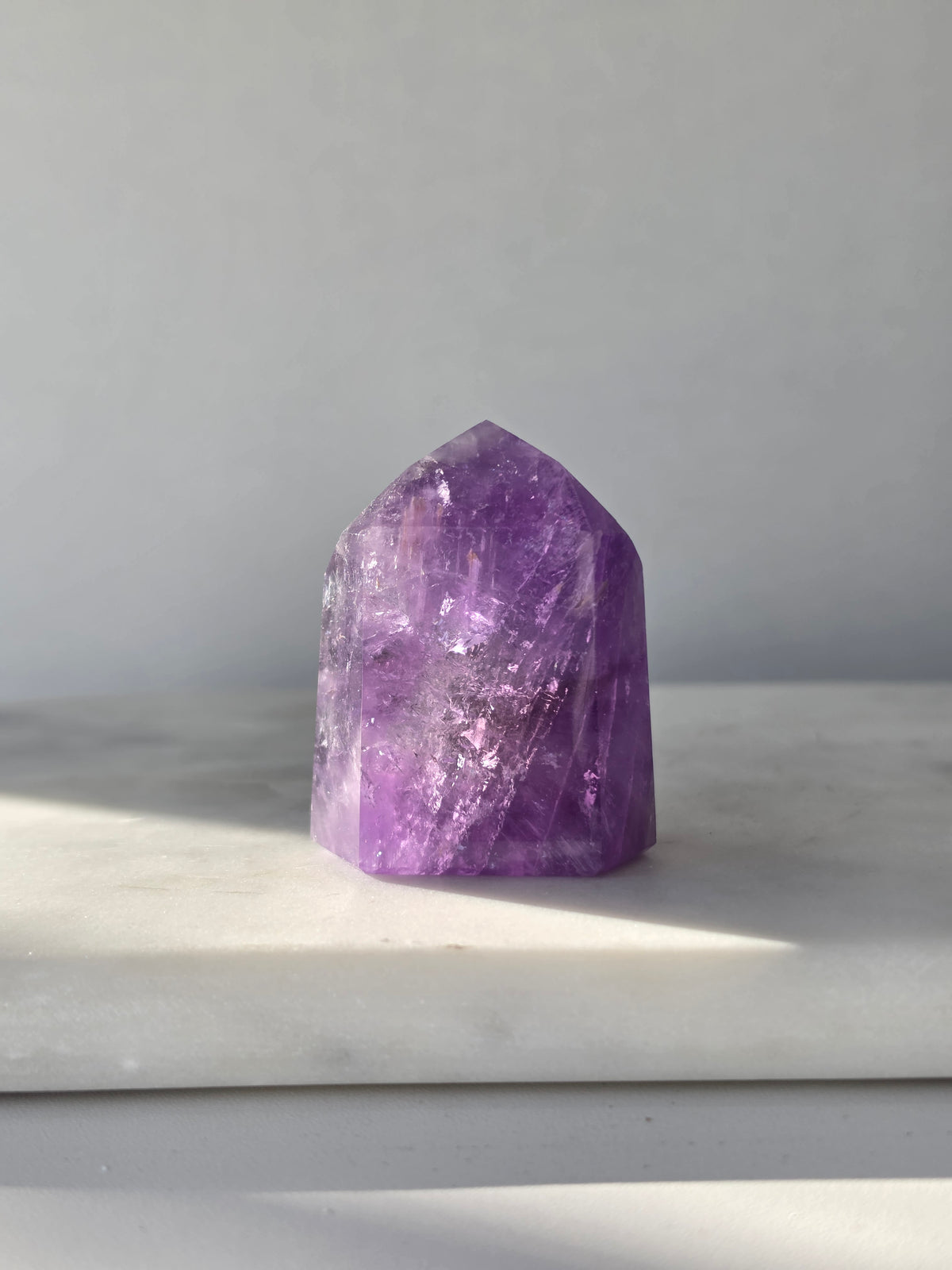 High clarity purple Amethyst tower from Brazil featuring rich violet and lavender hues, translucent crystal formations and polished reflective facets.