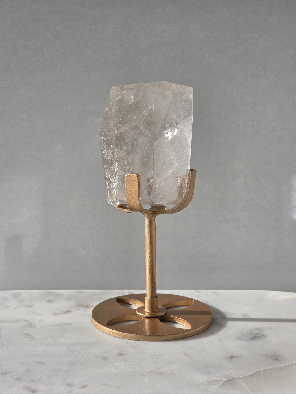 Clear Quartz freeform crystal with subtle smoky-grey translucence, natural internal inclusions and luminous clarity, displayed on an elegant gold-finished stand.