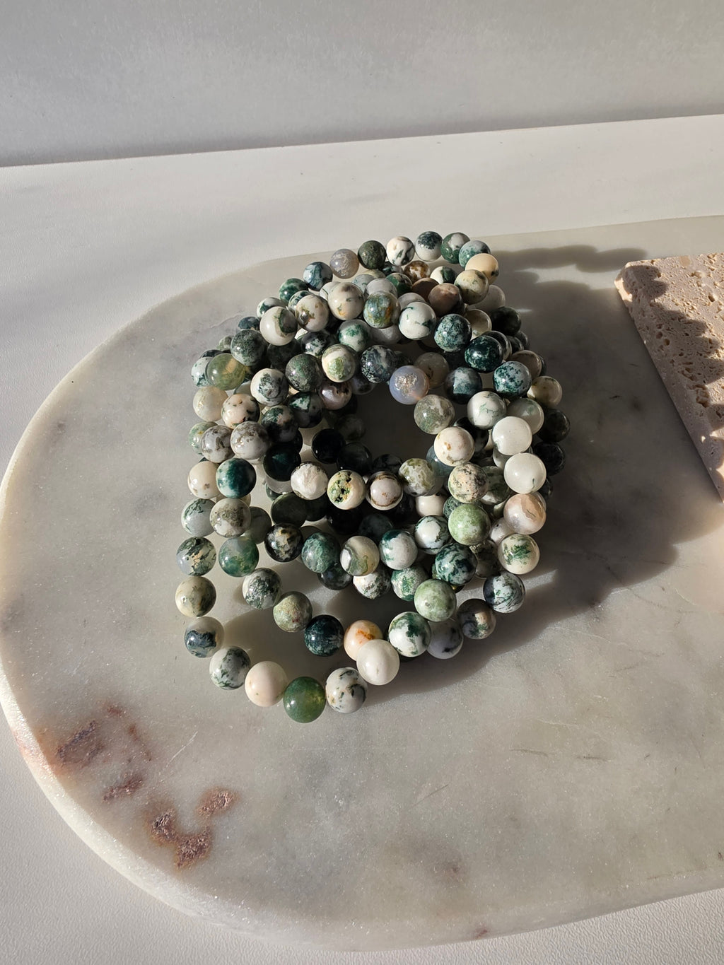 High-grade Moss Agate beaded bracelets featuring polished natural gemstones with rich forest green, soft ivory, and intricate moss-like inclusions, handcrafted with premium quality stones and photographed in natural light.