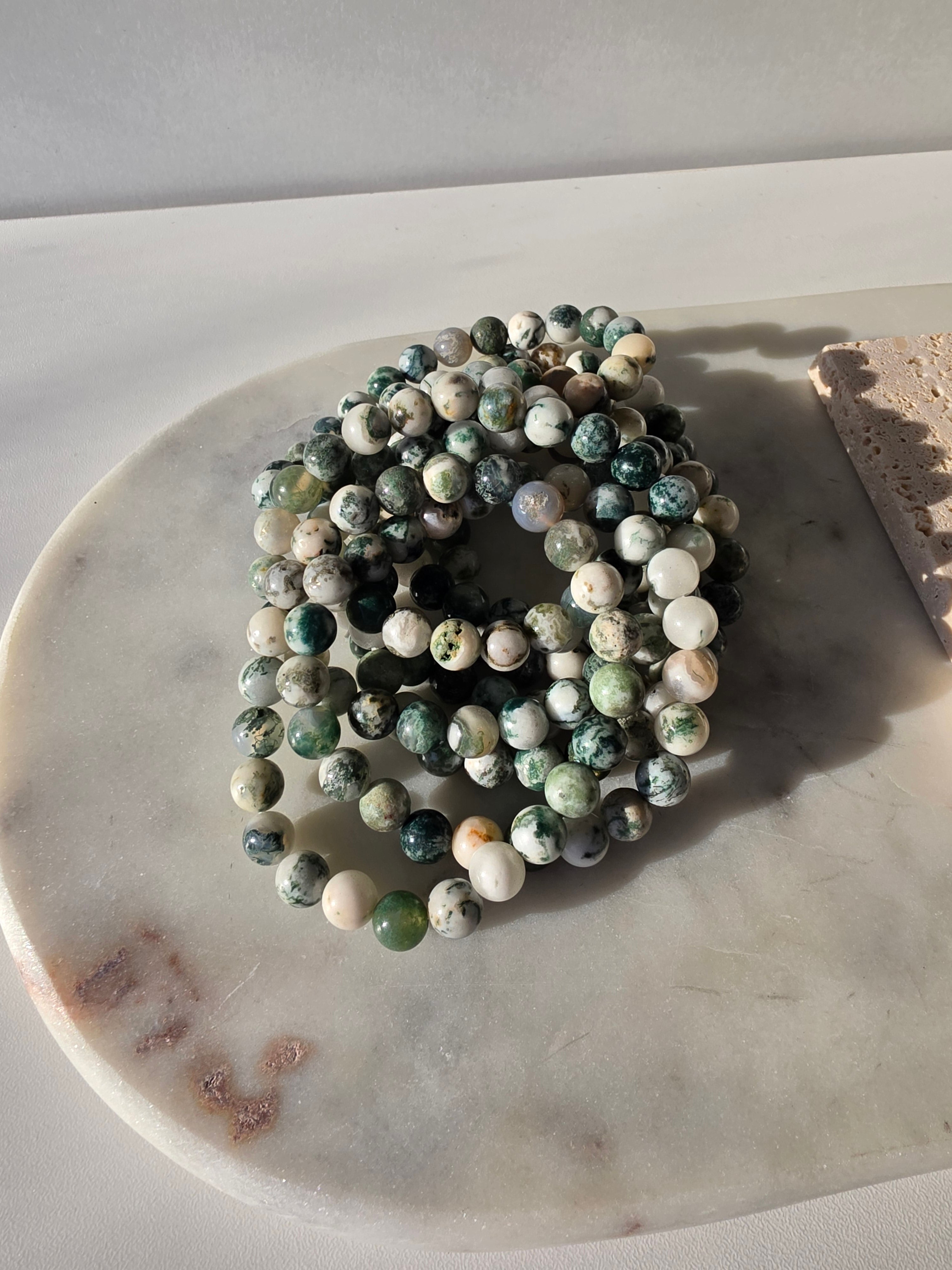 High-grade Moss Agate beaded bracelets featuring polished natural gemstones with rich forest green, soft ivory, and intricate moss-like inclusions, handcrafted with premium quality stones and photographed in natural light.