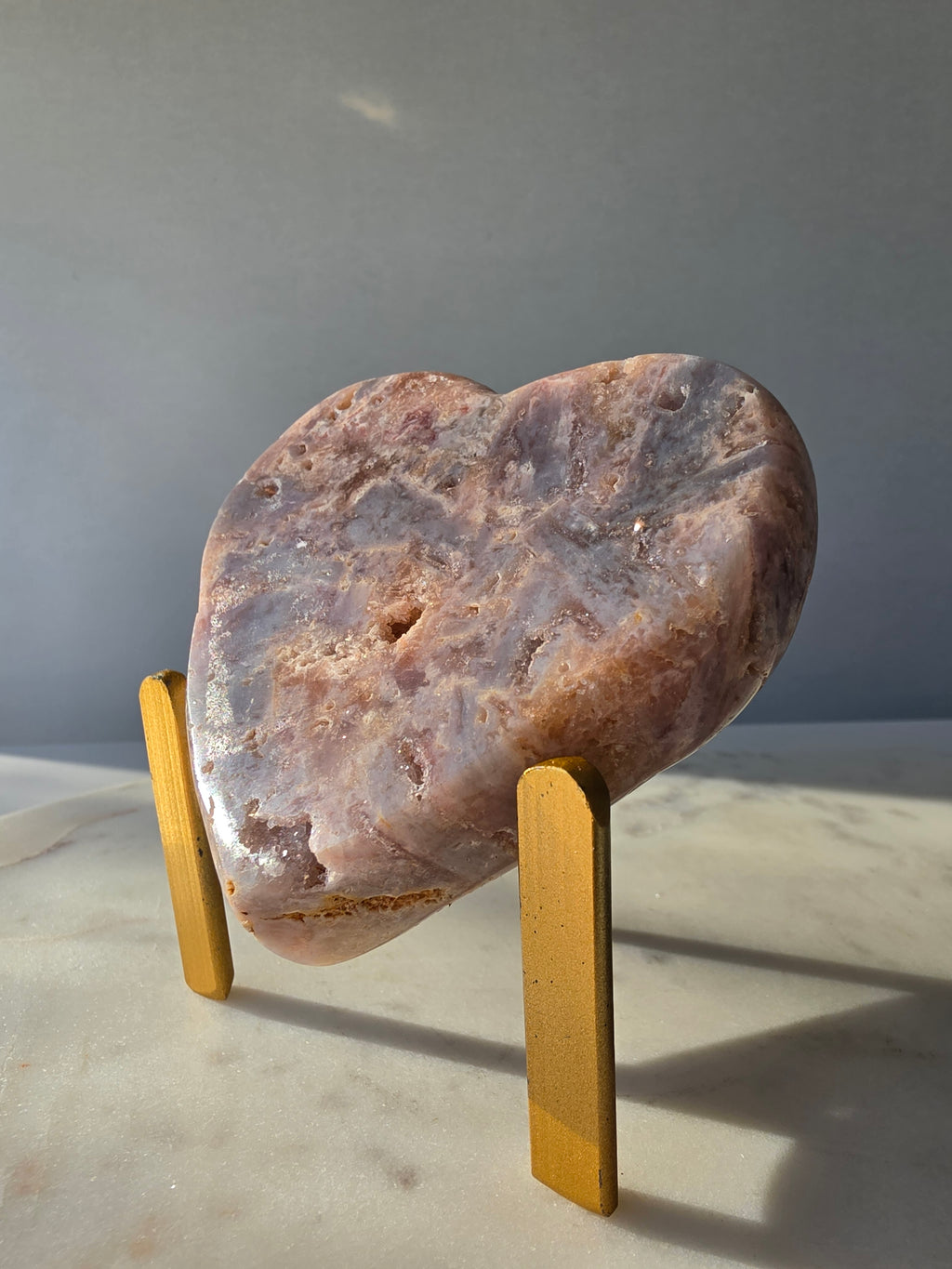 Pink Amethyst heart with soft pink and lilac colouring, intricate palhetados splinter-like formations, natural cavities and sparkling crystalline pockets on a gold stand