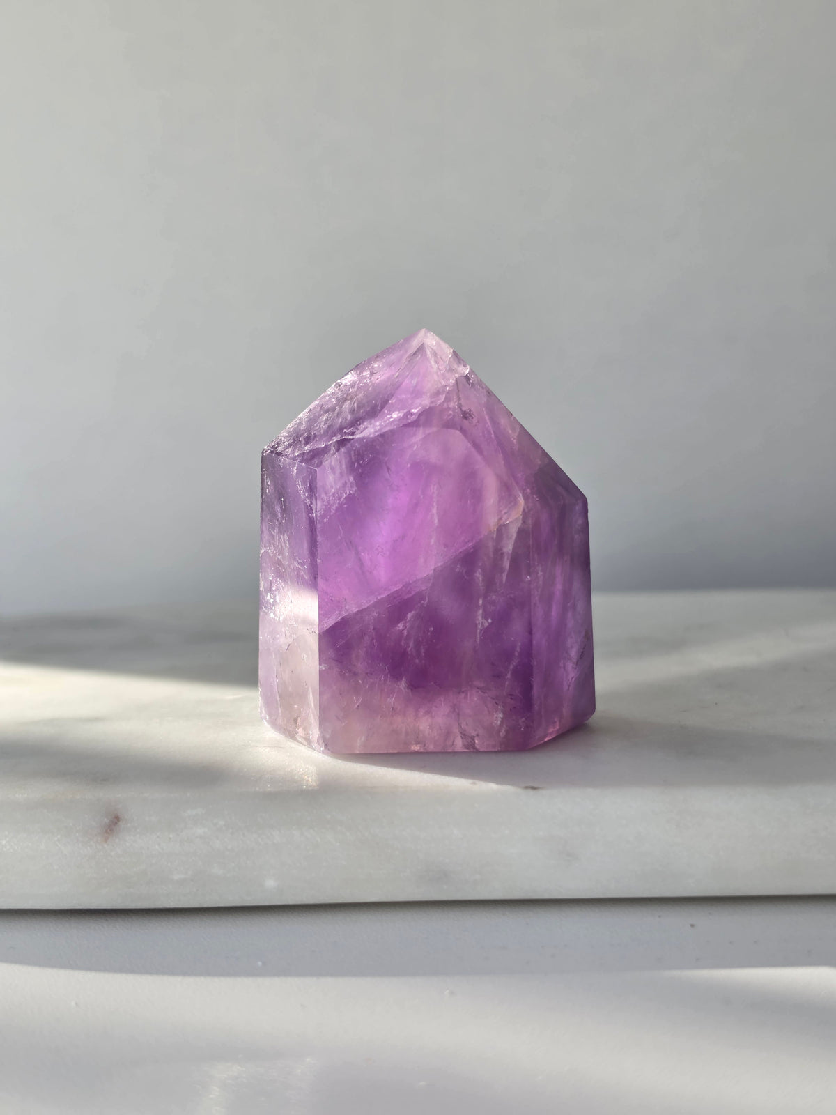 High clarity purple Amethyst tower from Brazil featuring rich violet and lavender hues, translucent crystal formations and polished reflective facets.
