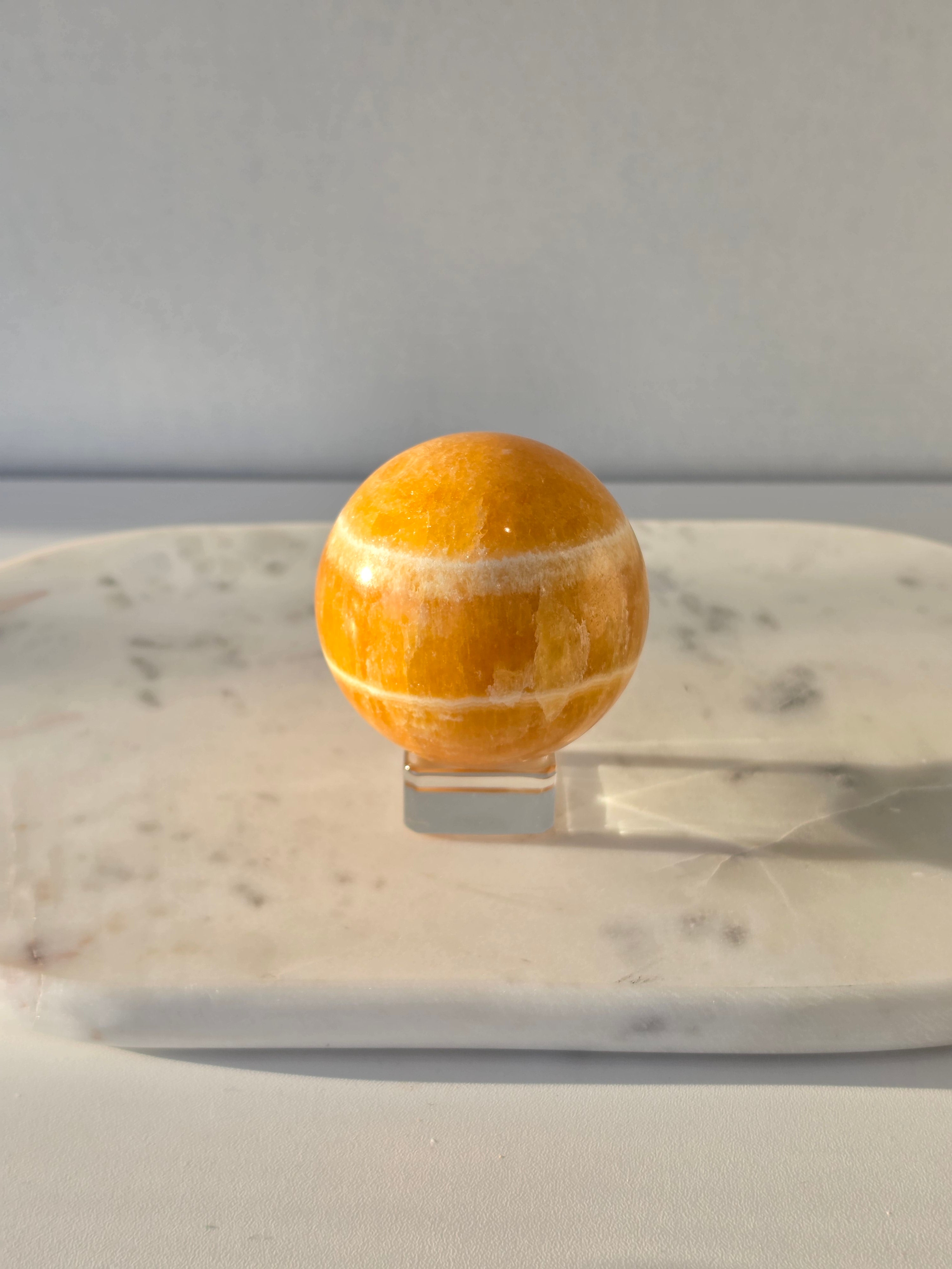 Natural Orange Calcite Sphere with warm golden-orange banding, polished to a high shine and hand-selected by Stone & Bloom.