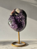 Natural Amethyst Stalactite with Calcite inclusions and blush red tones on a luxury gold display stand