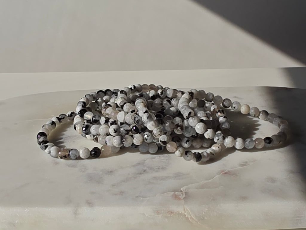 Natural Rainbow Moonstone bracelet featuring polished milky beads with soft translucent tones and luminous blue iridescent flashes