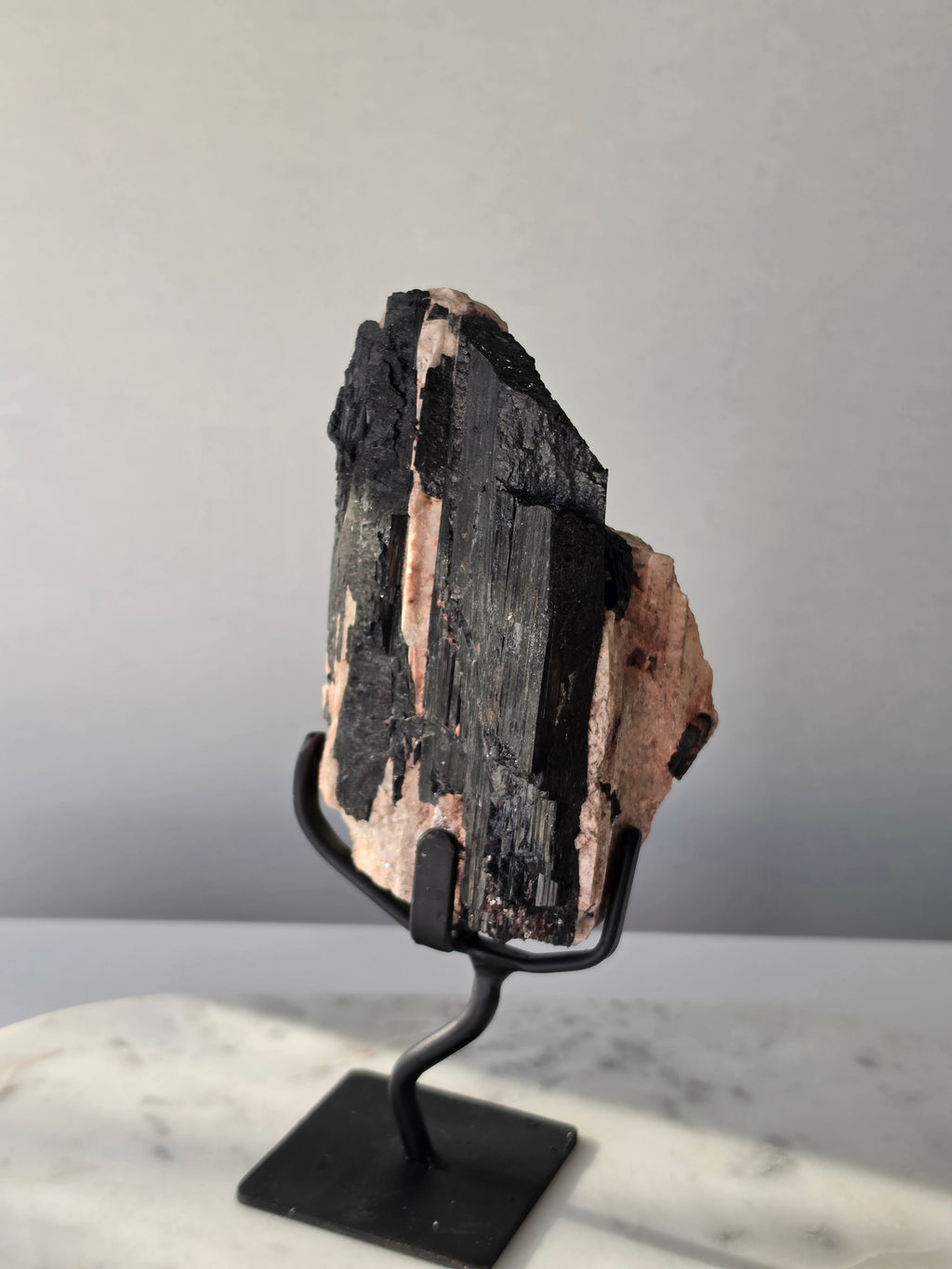 Black Tourmaline on Feldspar matrix from Brazil featuring naturally formed black crystals, contrasting pale matrix, black display stand, 910g, 19.5 × 6.5cm.